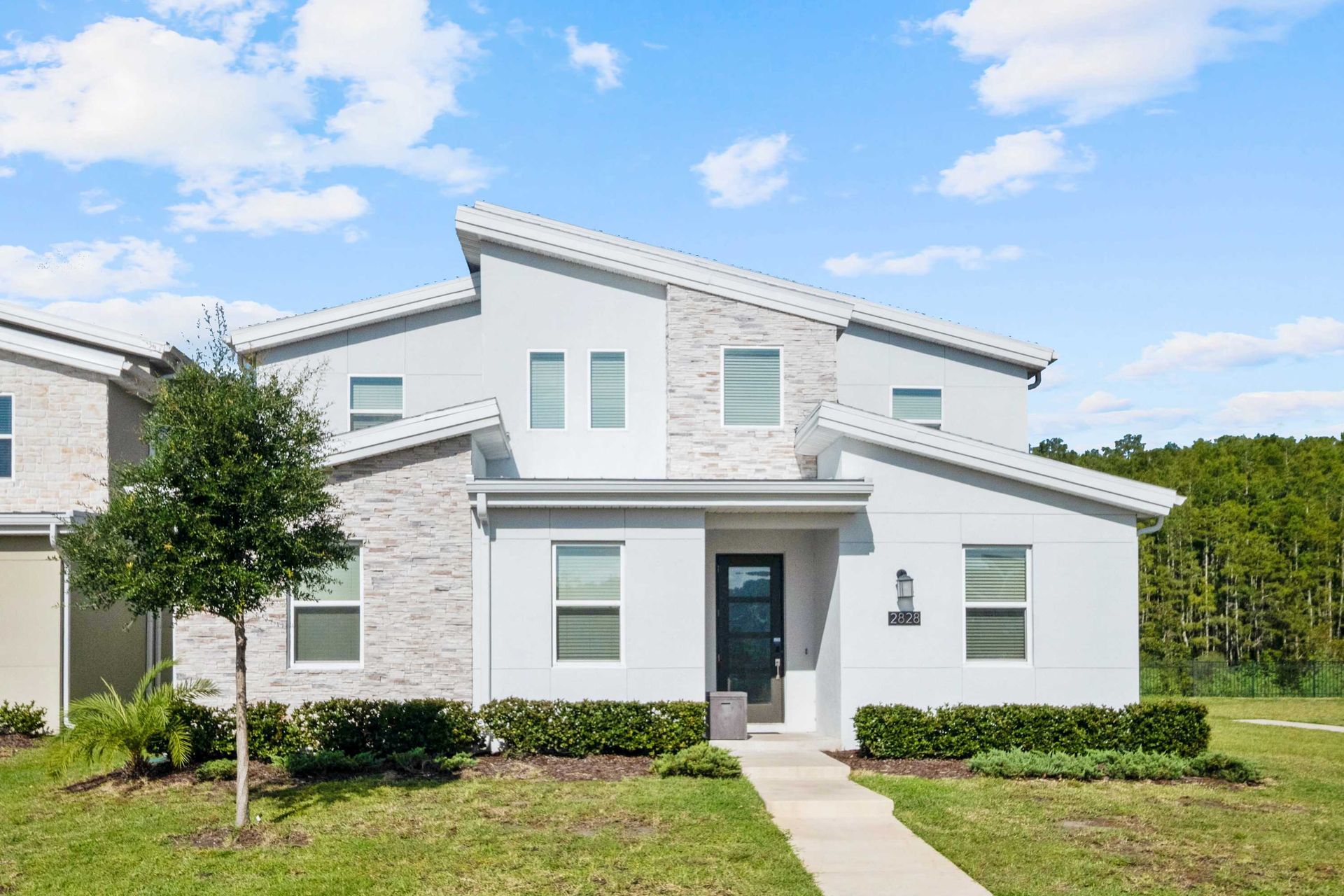 Stunning modern home with unique angular roofs and stone accents.