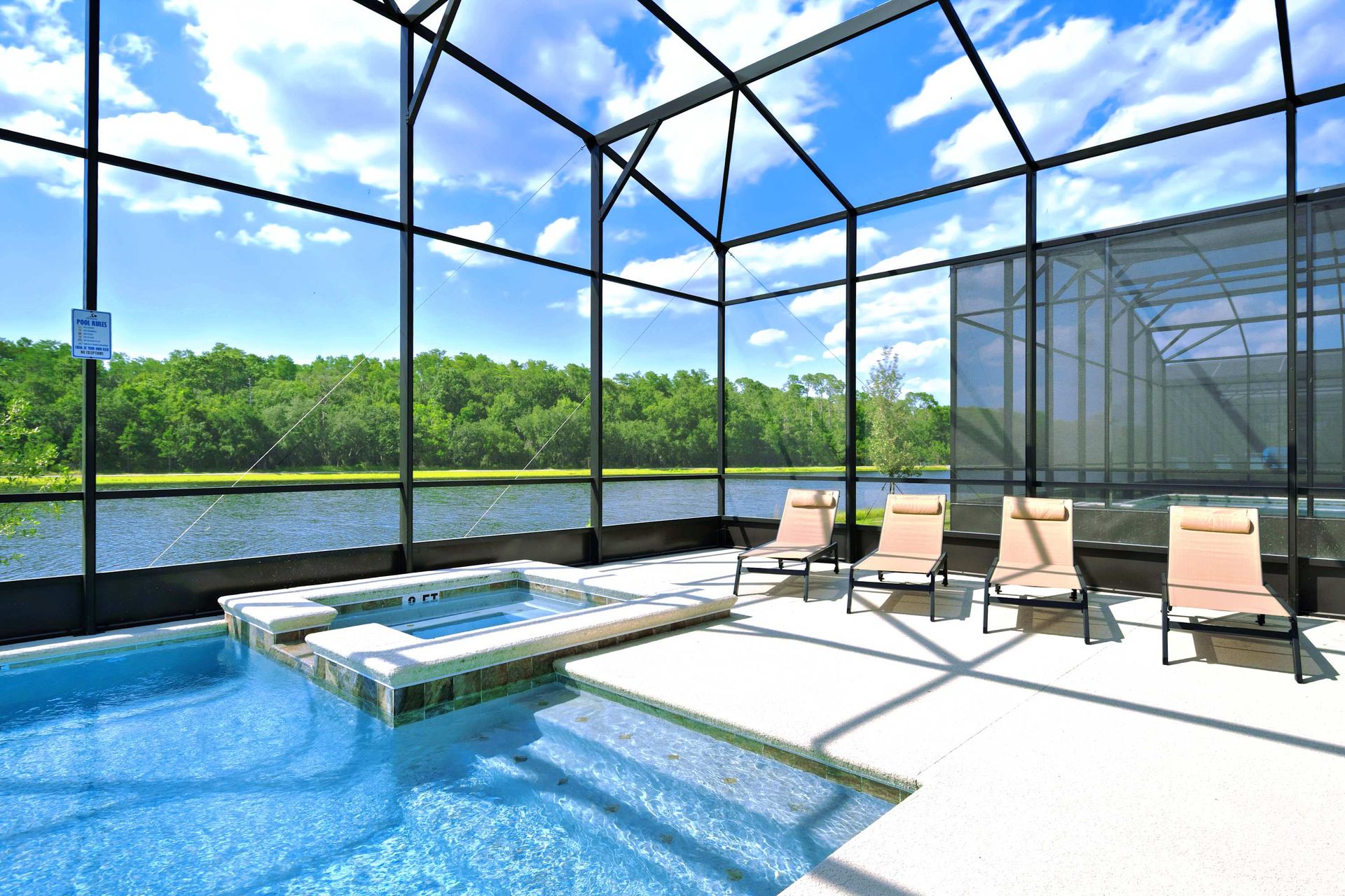 Screened pool and spa with sun loungers and a serene lake view. 