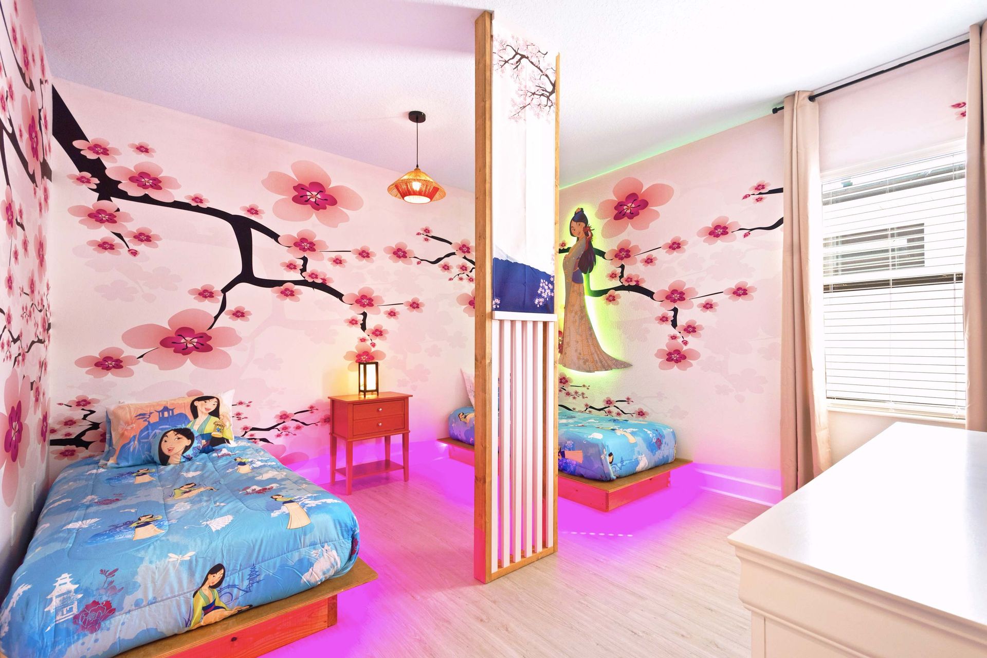 Twin beds separated by a screen, with stunning cherry blossom art.