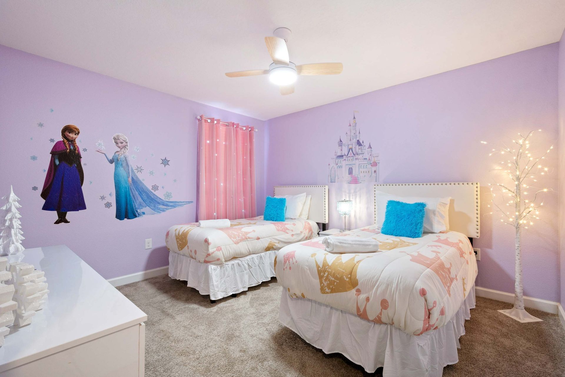 Twin beds in a magical themed room with princess art and fairy lights.