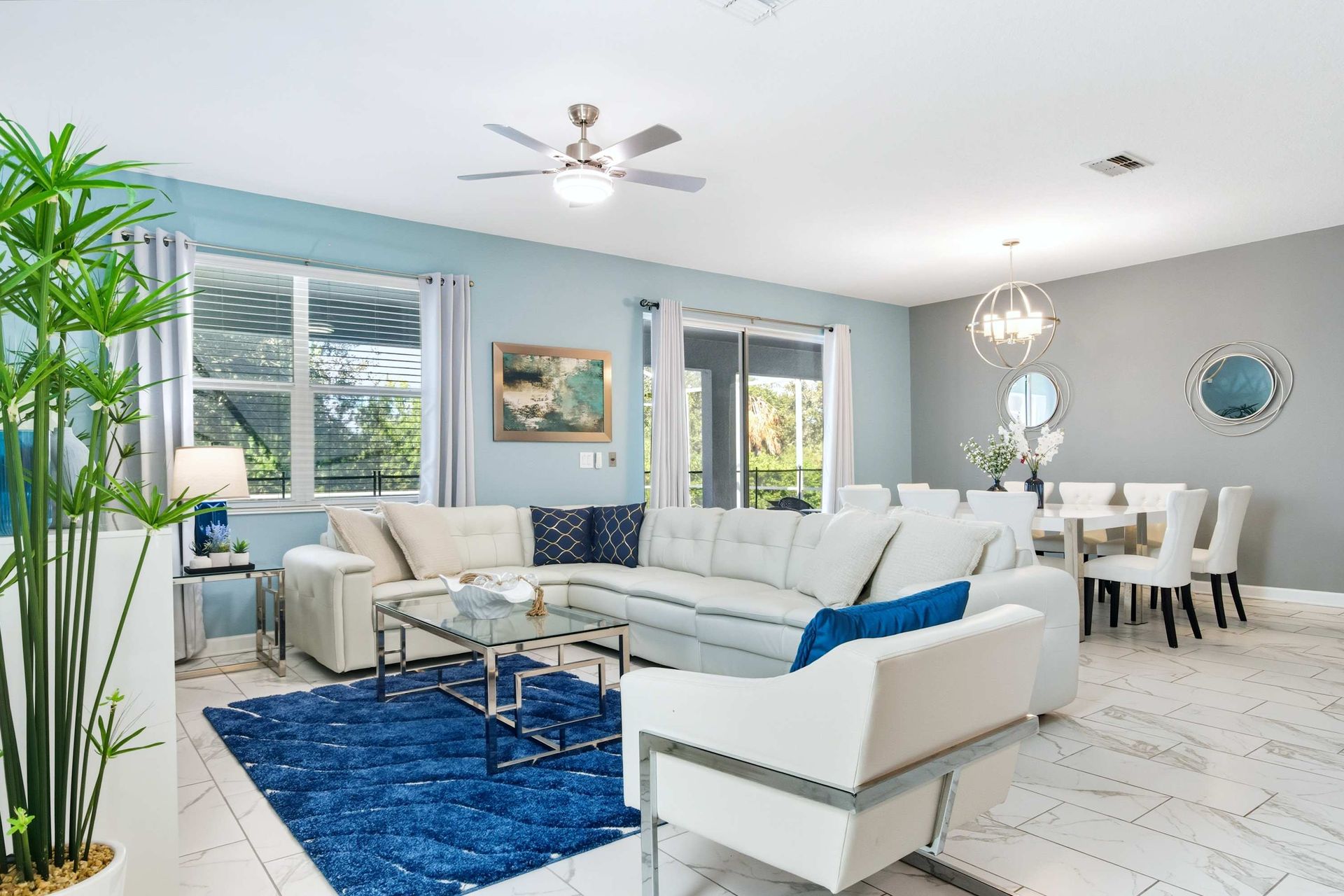 Airy lounge with white sectional, bold blue rug, and patio access.