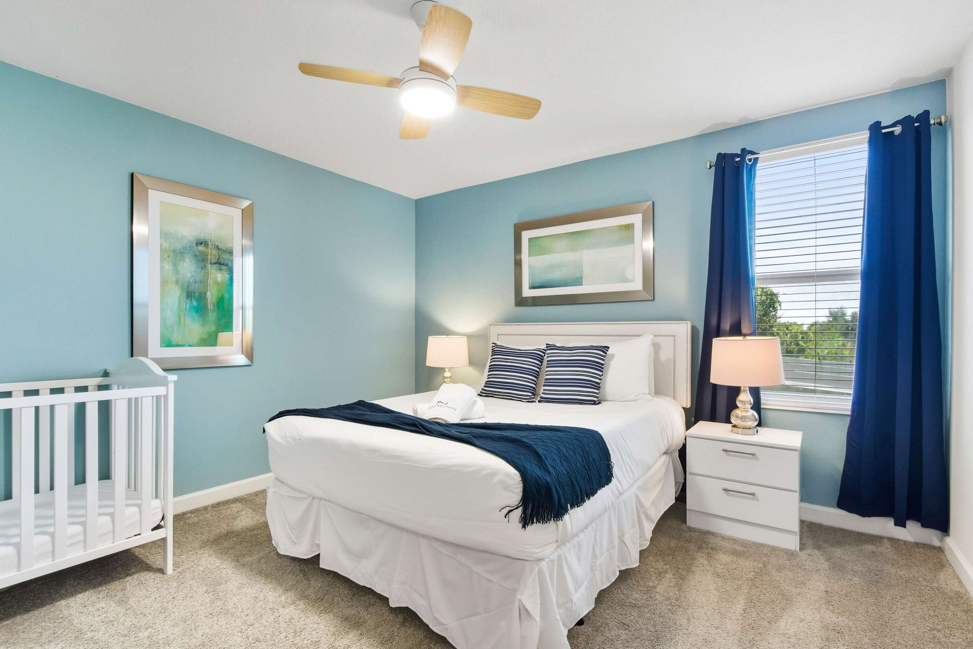 Plush Queen bed and crib in a serene room with cool blue tones.