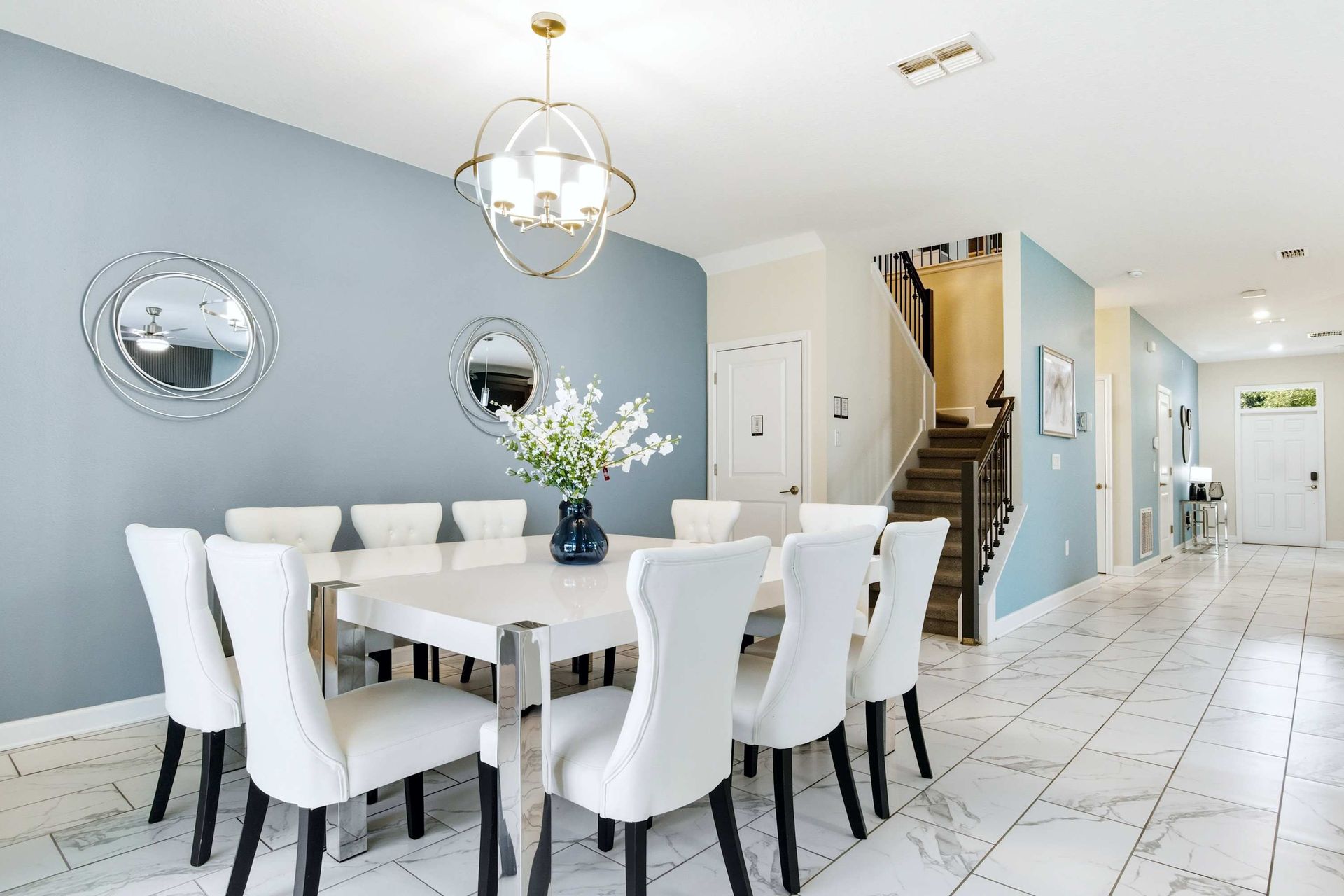 Chic white table, plush chairs, and modern mirrored art.