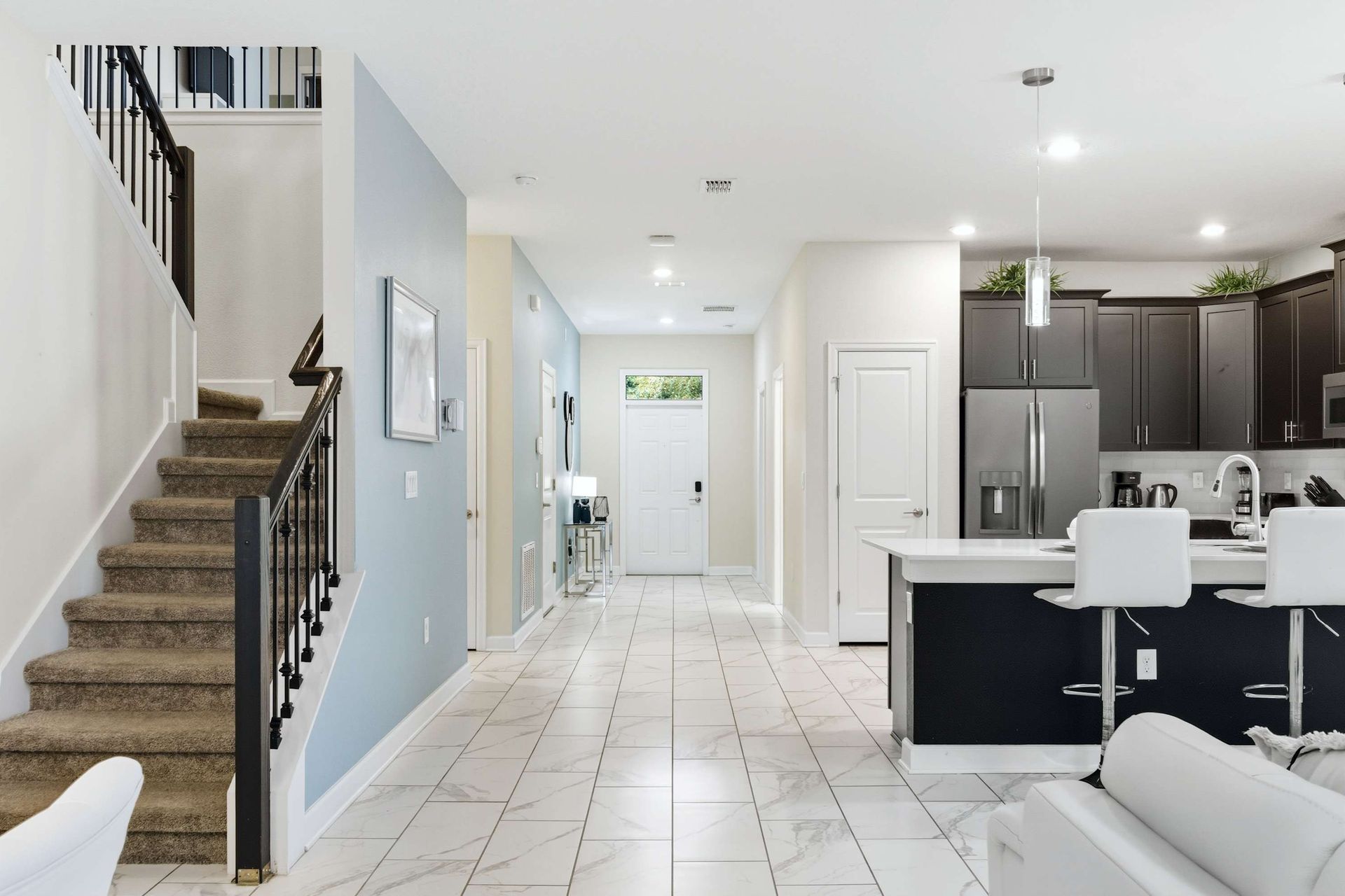 Open floor plan: bright entry, grand staircase, and modern kitchen bar.