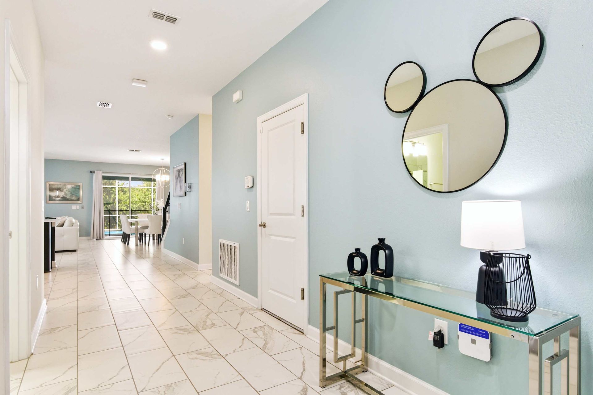 Chic entry hall with a fun mirror, modern console, and cool blue walls.