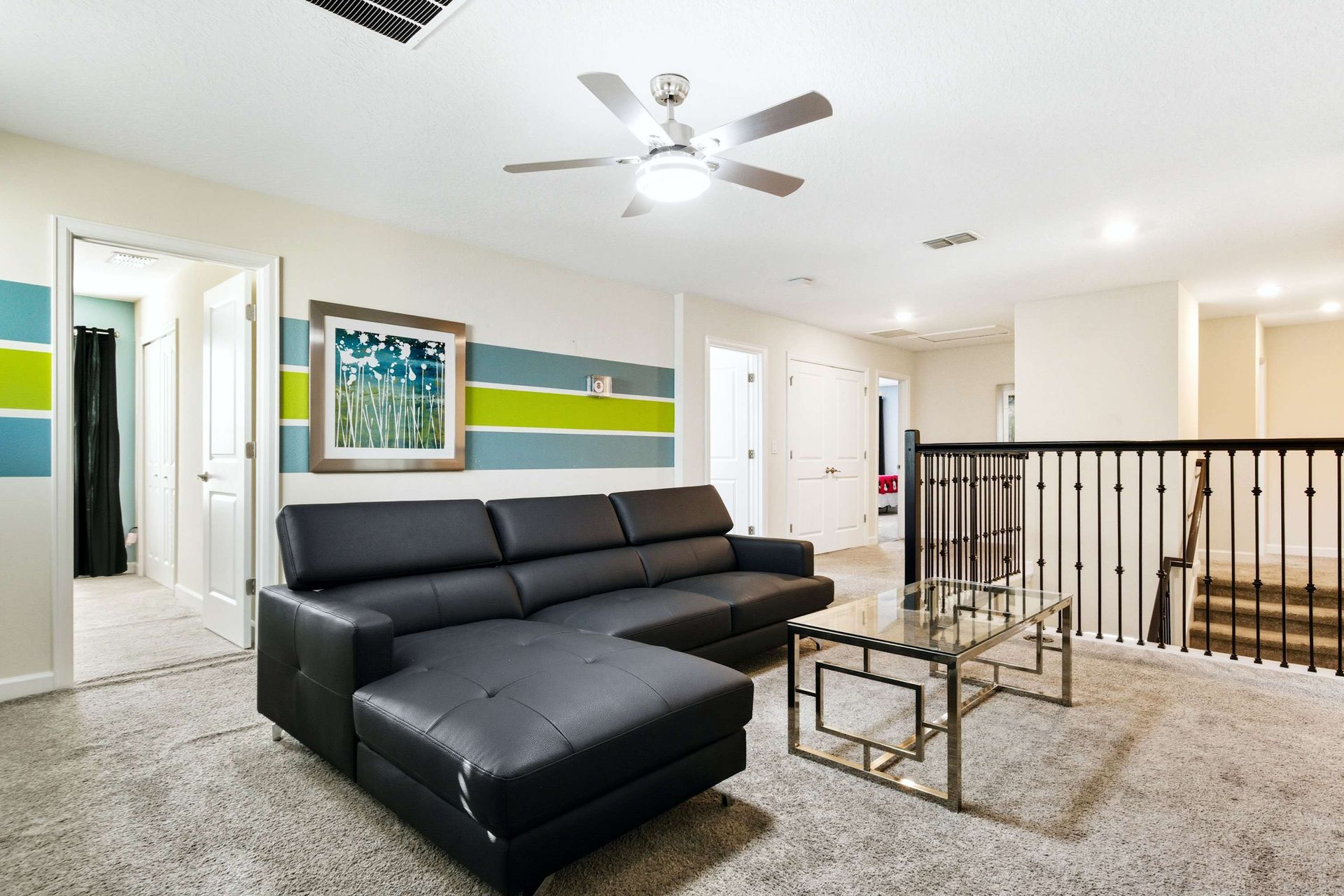 Cozy black sectional in the upstairs loft with fun accent wall and railing.