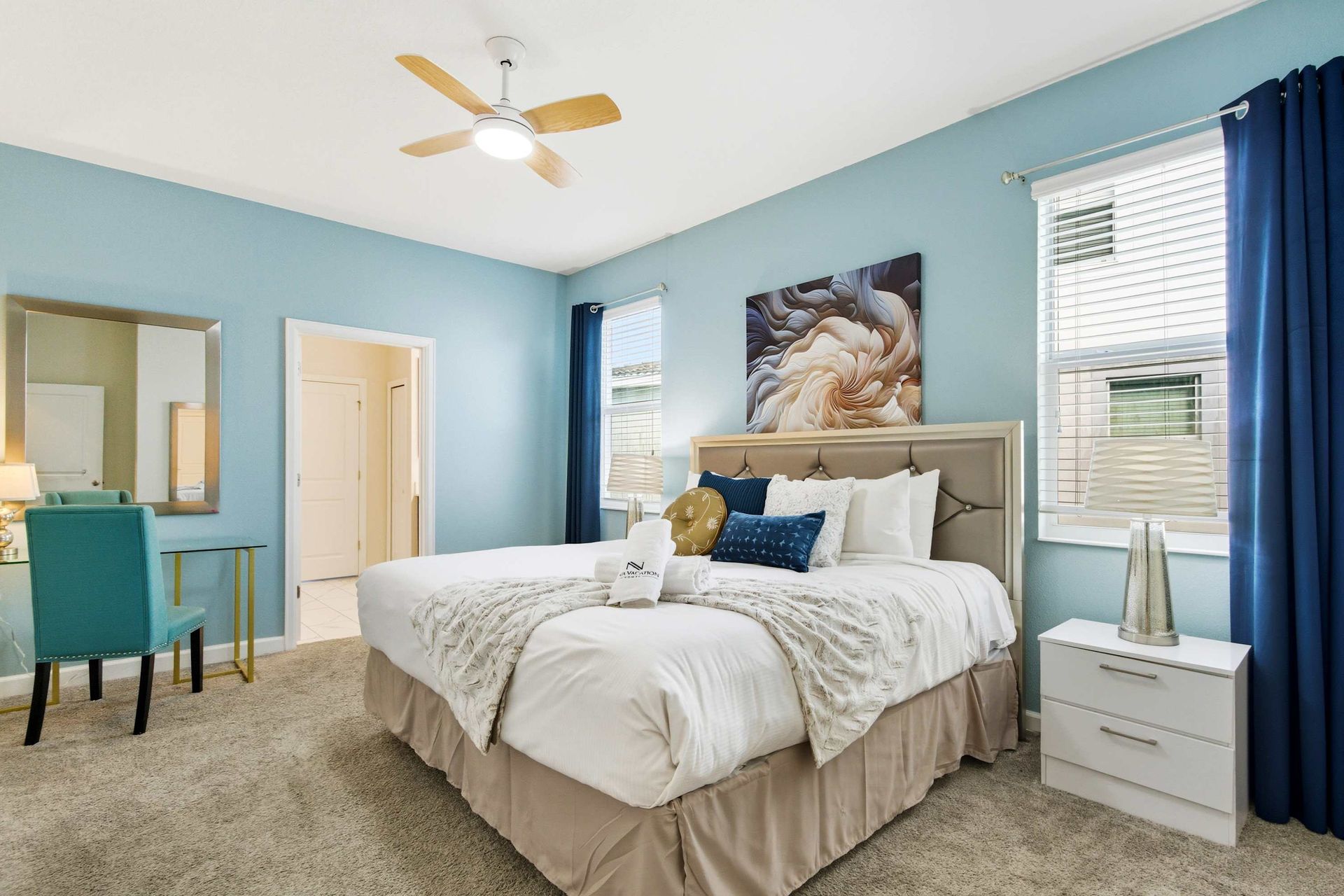 Serene Queen suite with plush bed, ceiling fan, and cool blue palette.