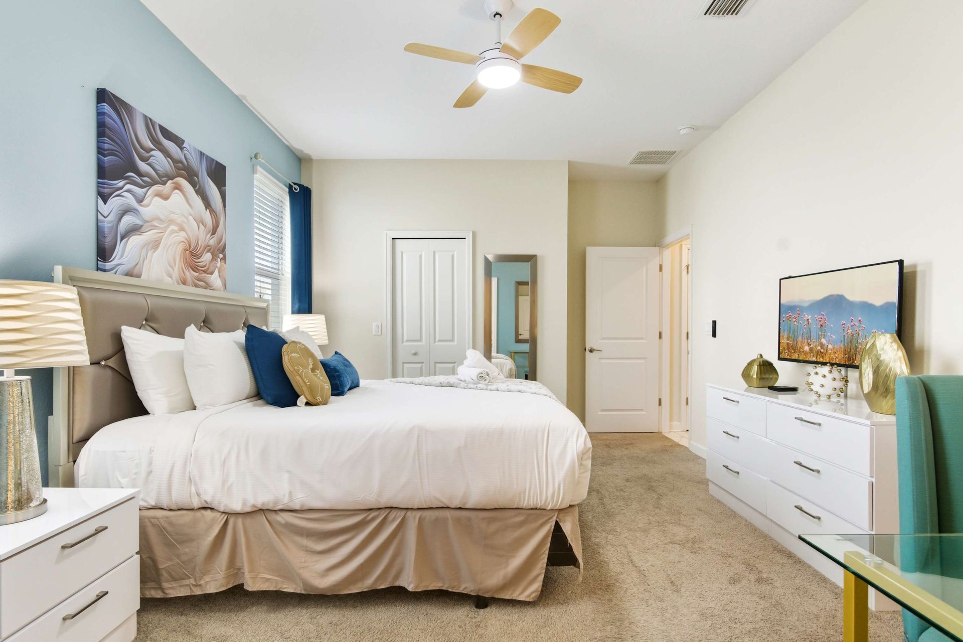 Plush King suite with blue accent wall, bold art, and ample storage.