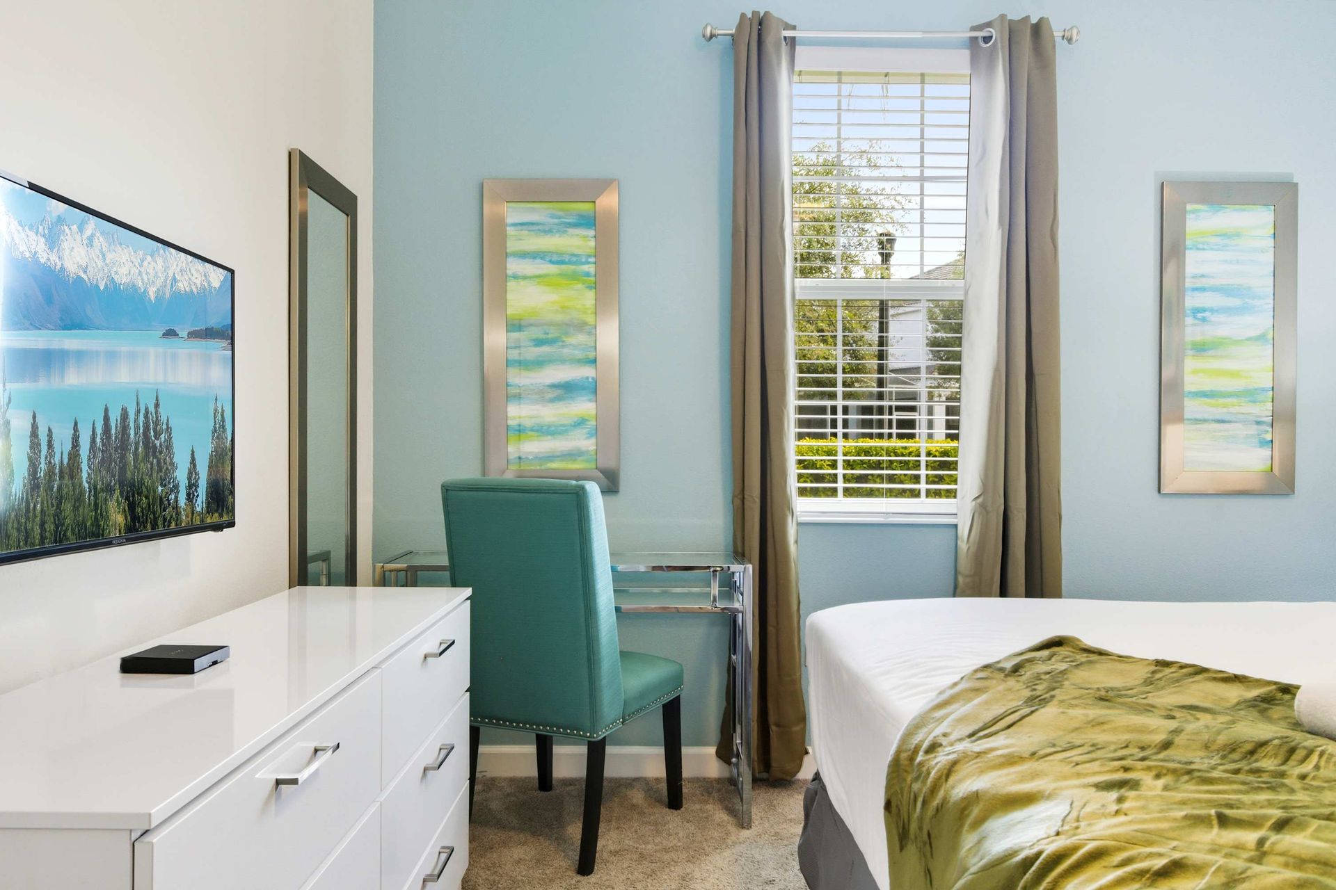 Cool blue walls, sleek white dresser, and a dedicated vanity/desk.