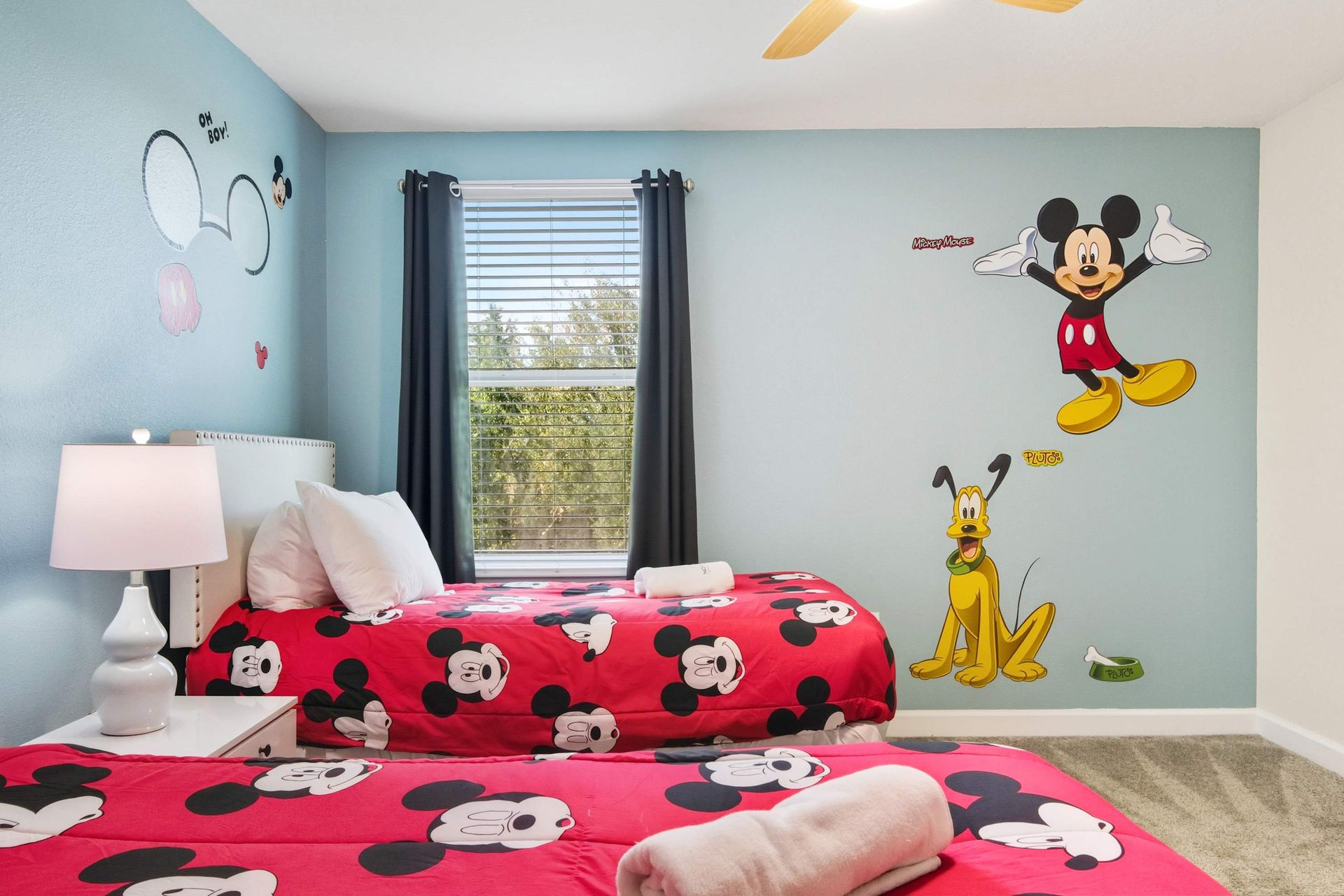 Twin beds in a vibrant Mickey Mouse and Pluto themed room.