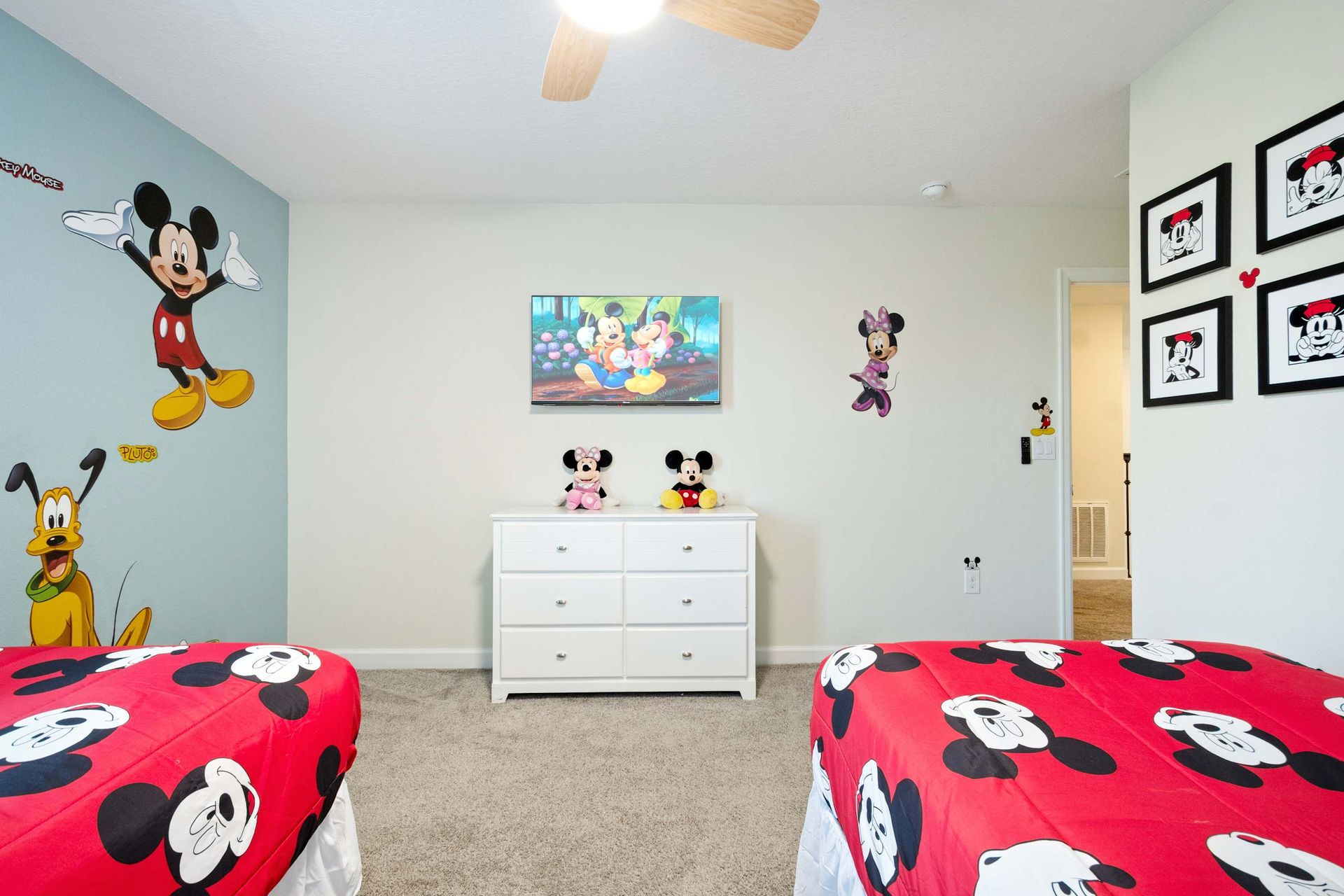 Twin beds in a vibrant Mickey Mouse-themed room with a flat-screen TV. (