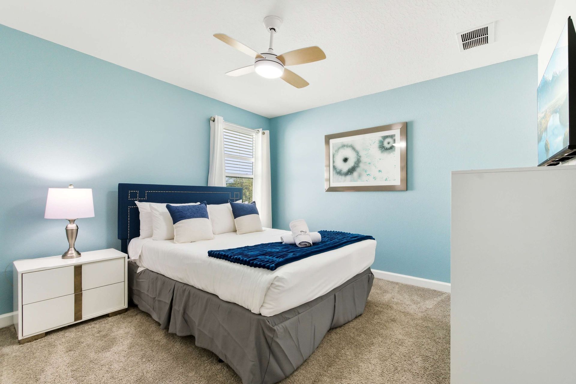 Bright, modern Queen room with blue accents and a flat-screen TV.