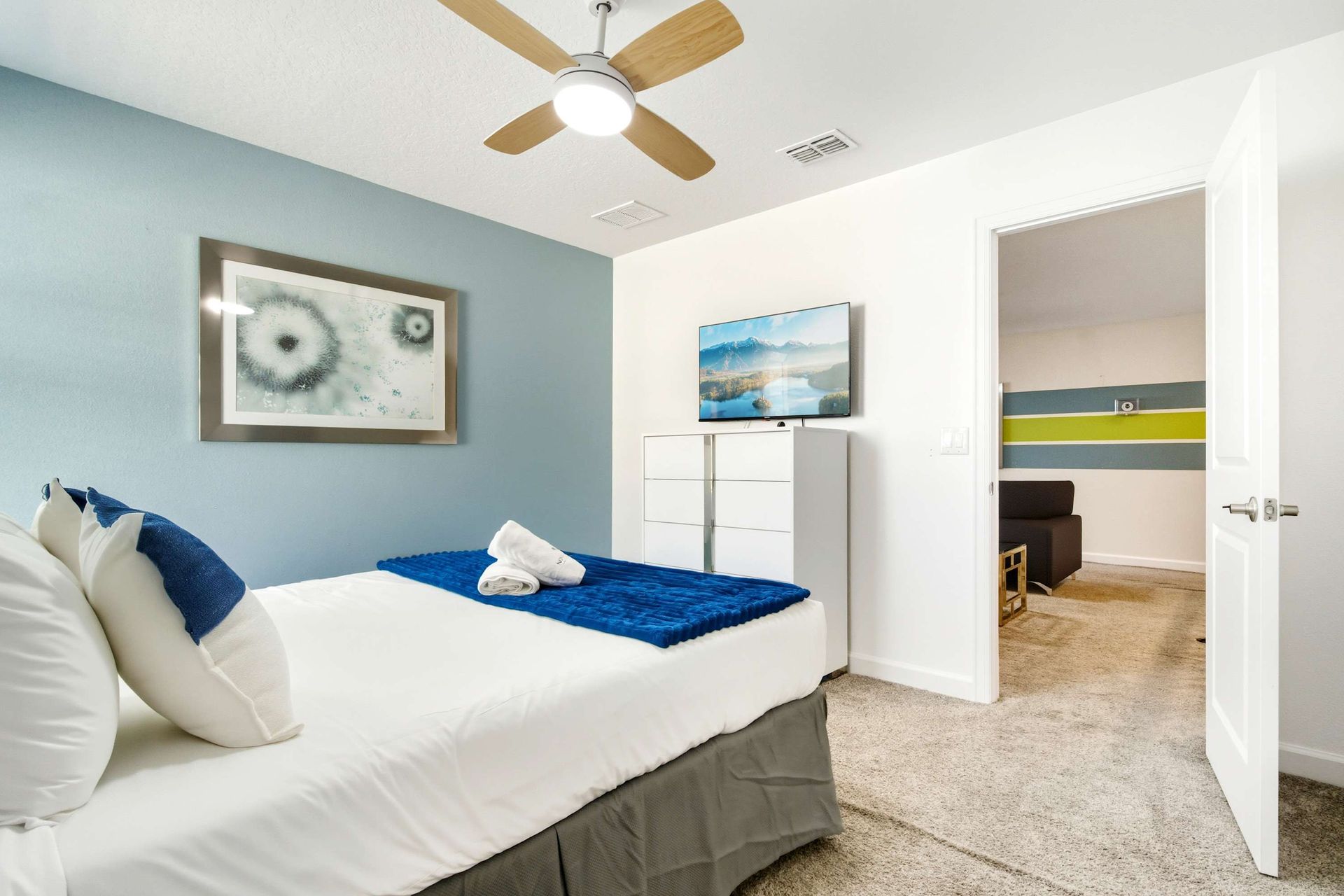 Serene Queen bed with a calming blue accent wall and large TV.