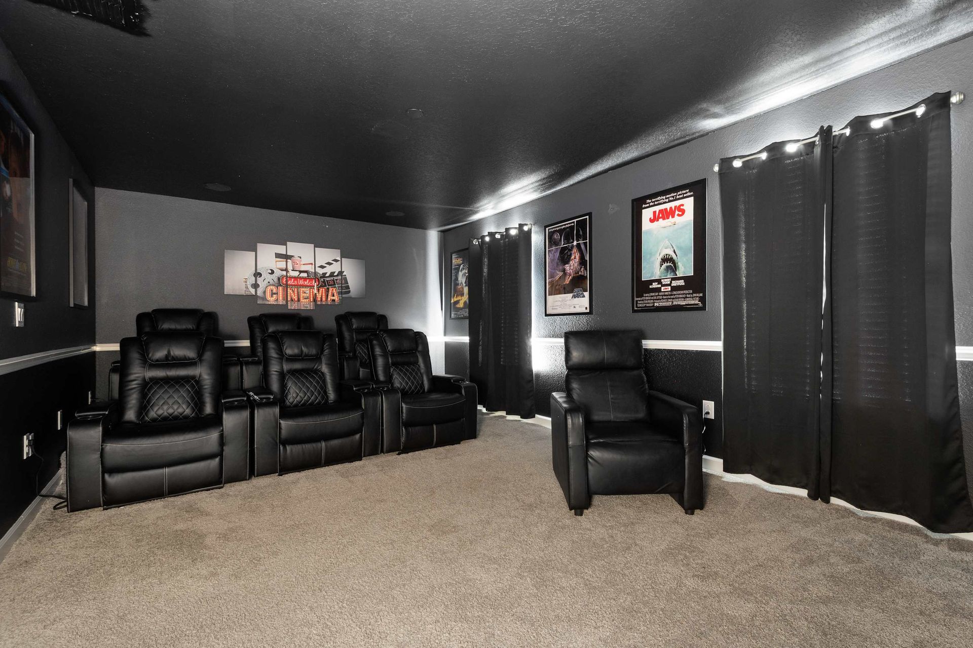 Theater room with plush leather recliners and blackout curtains.