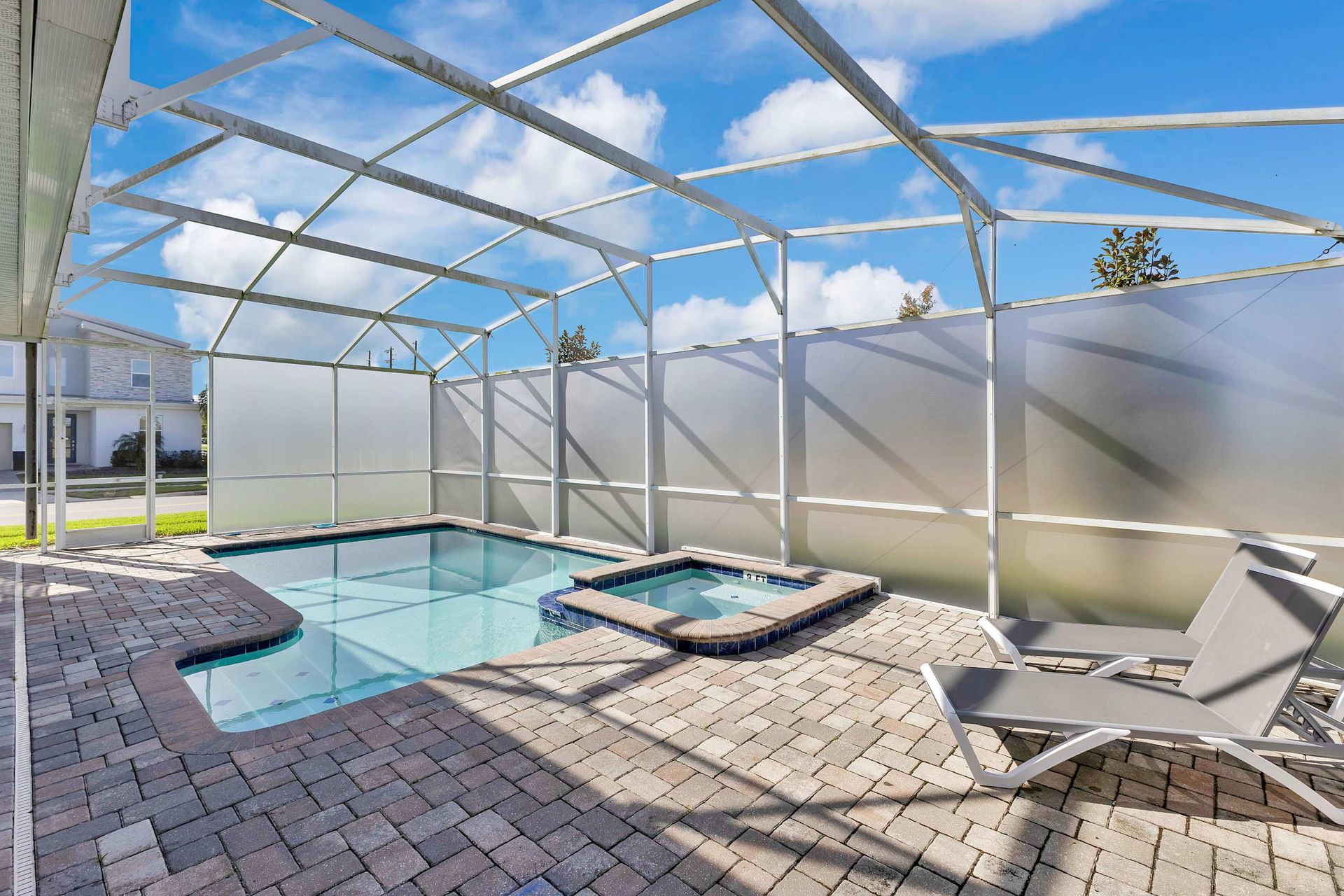 Bright resort clubhouse entrance with palm trees, manicured landscaping, and a driveway.