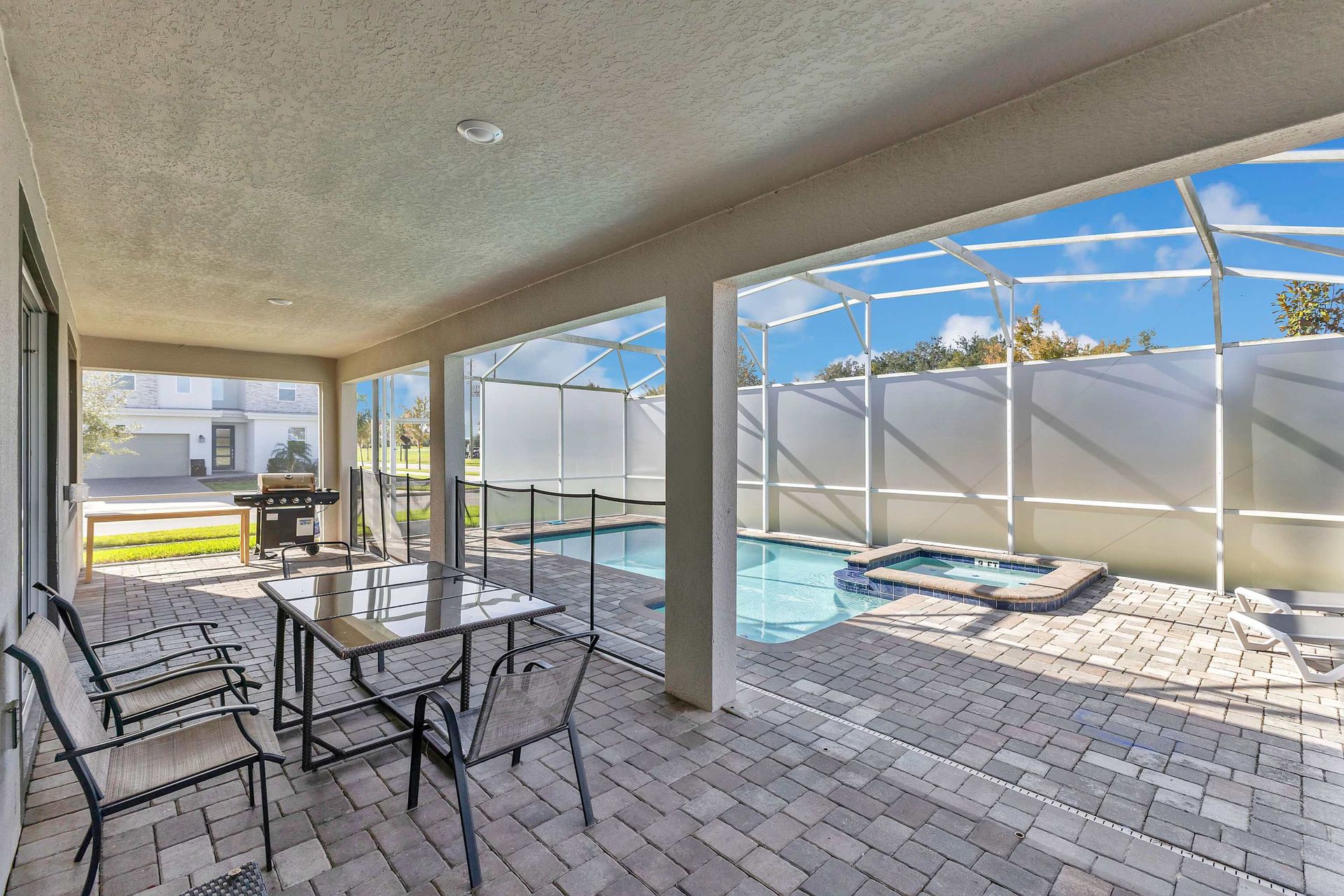 A private villa's screened-in patio, dining area, grill, and swimming pool with a spa.