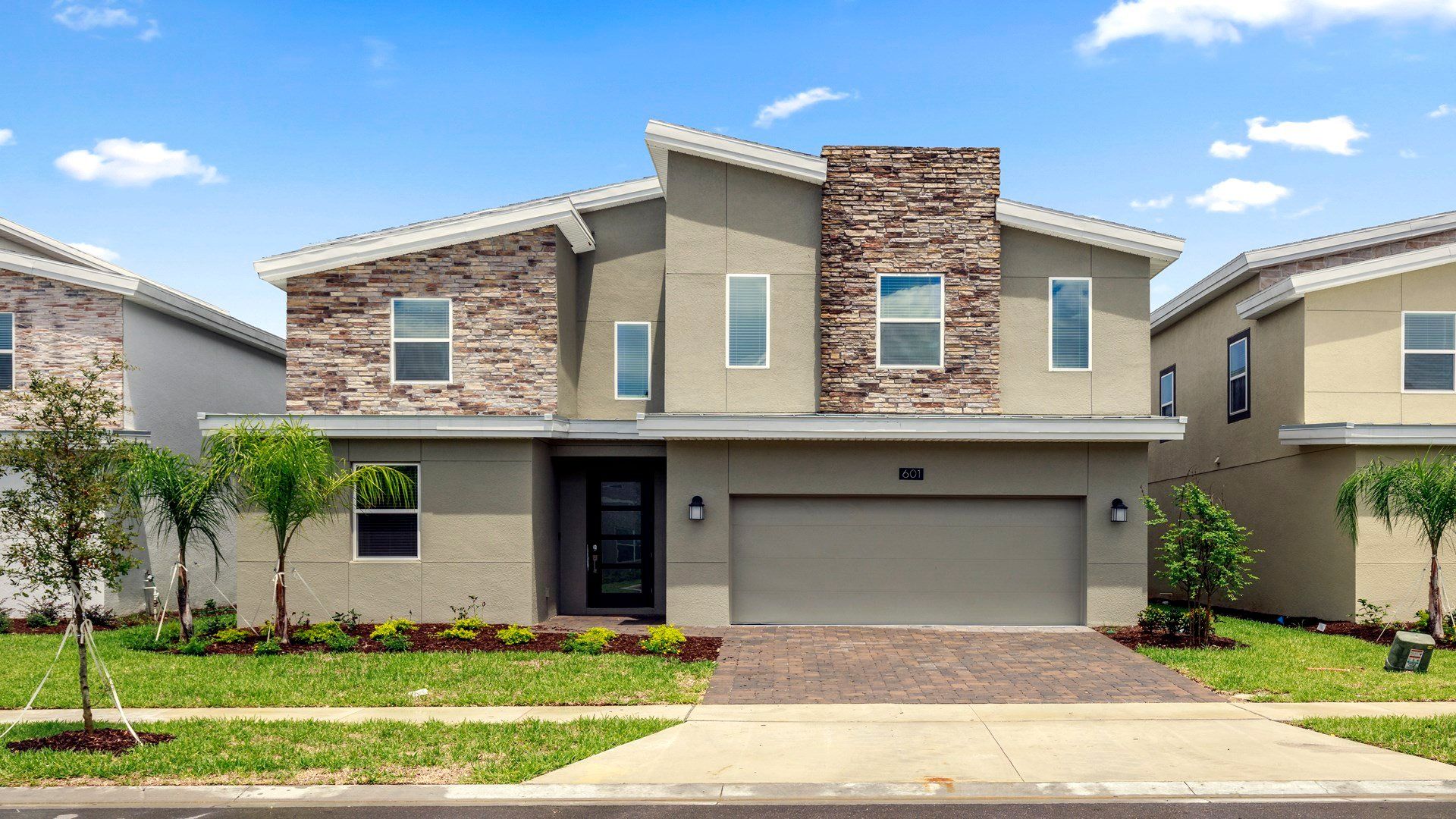 Modern two-story home with a spacious driveway and lush landscaping