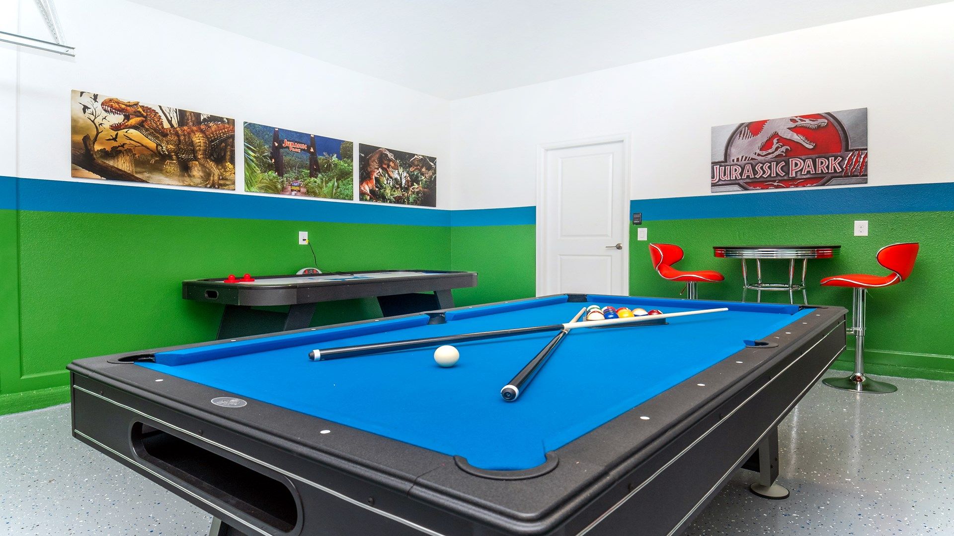 Fun Jurassic-themed game room with pool table, air hockey, and seating.