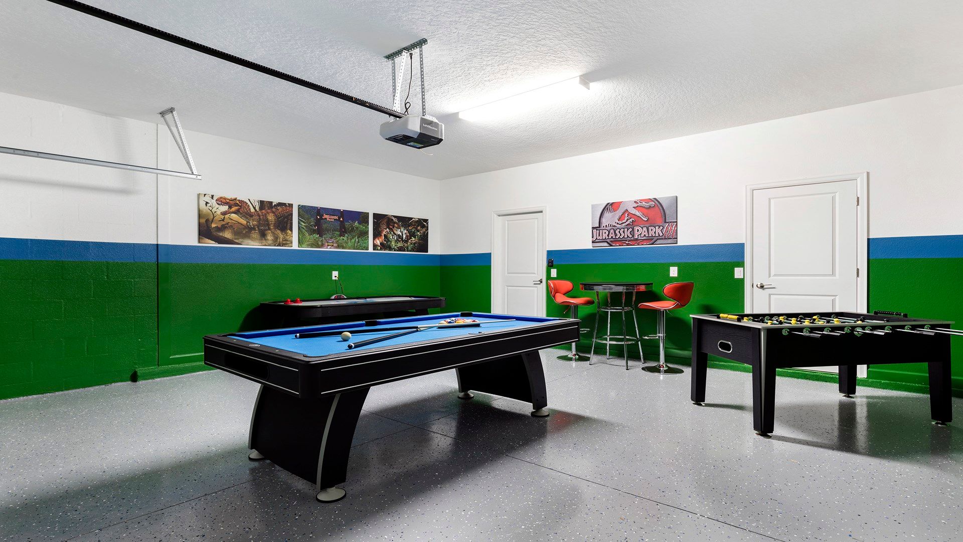 Fun Jurassic-themed game room with pool table, air hockey, and seating.