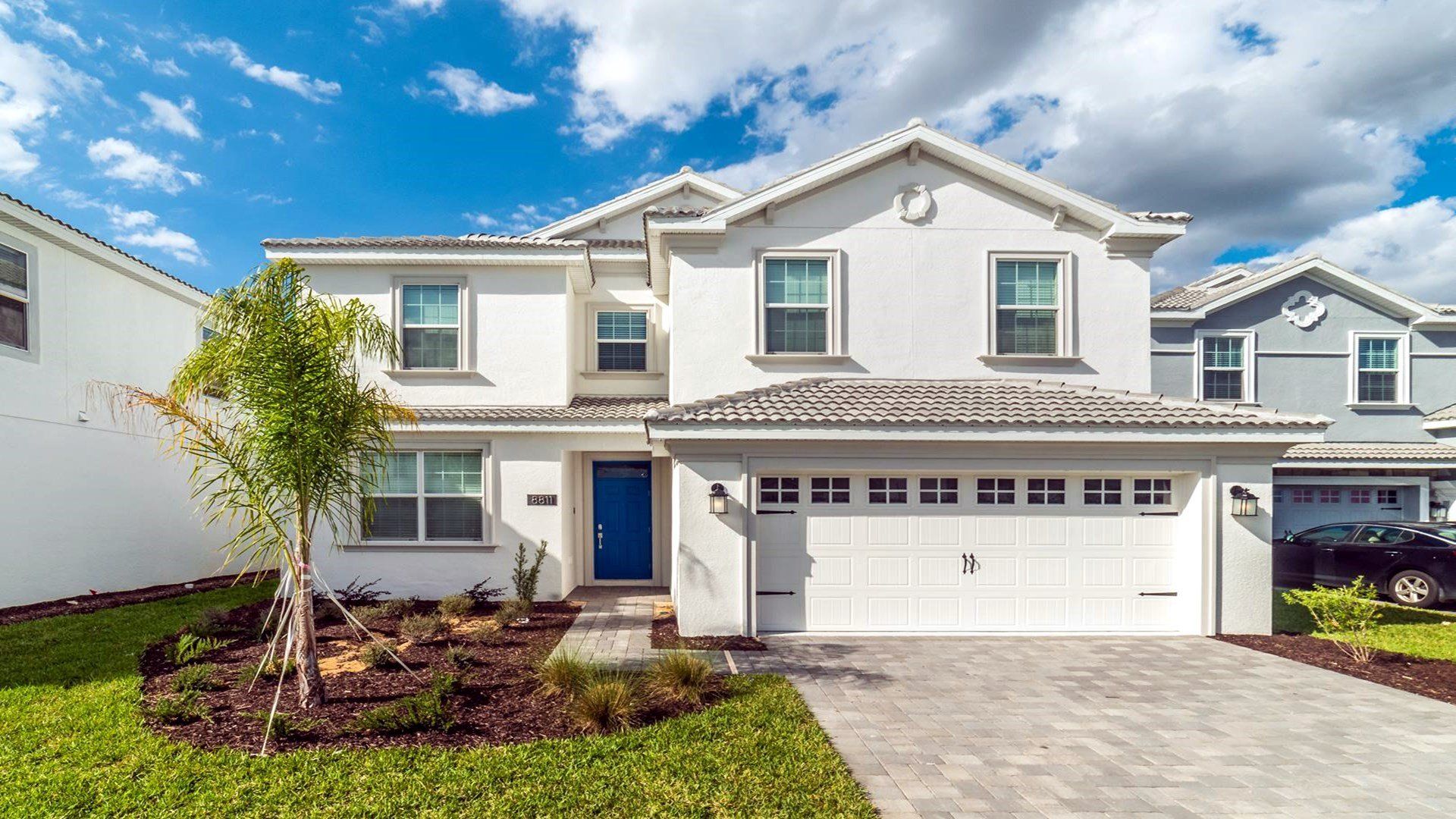 Modern 2-story villa with 2-car garage, fresh landscaping, and bright blue door.