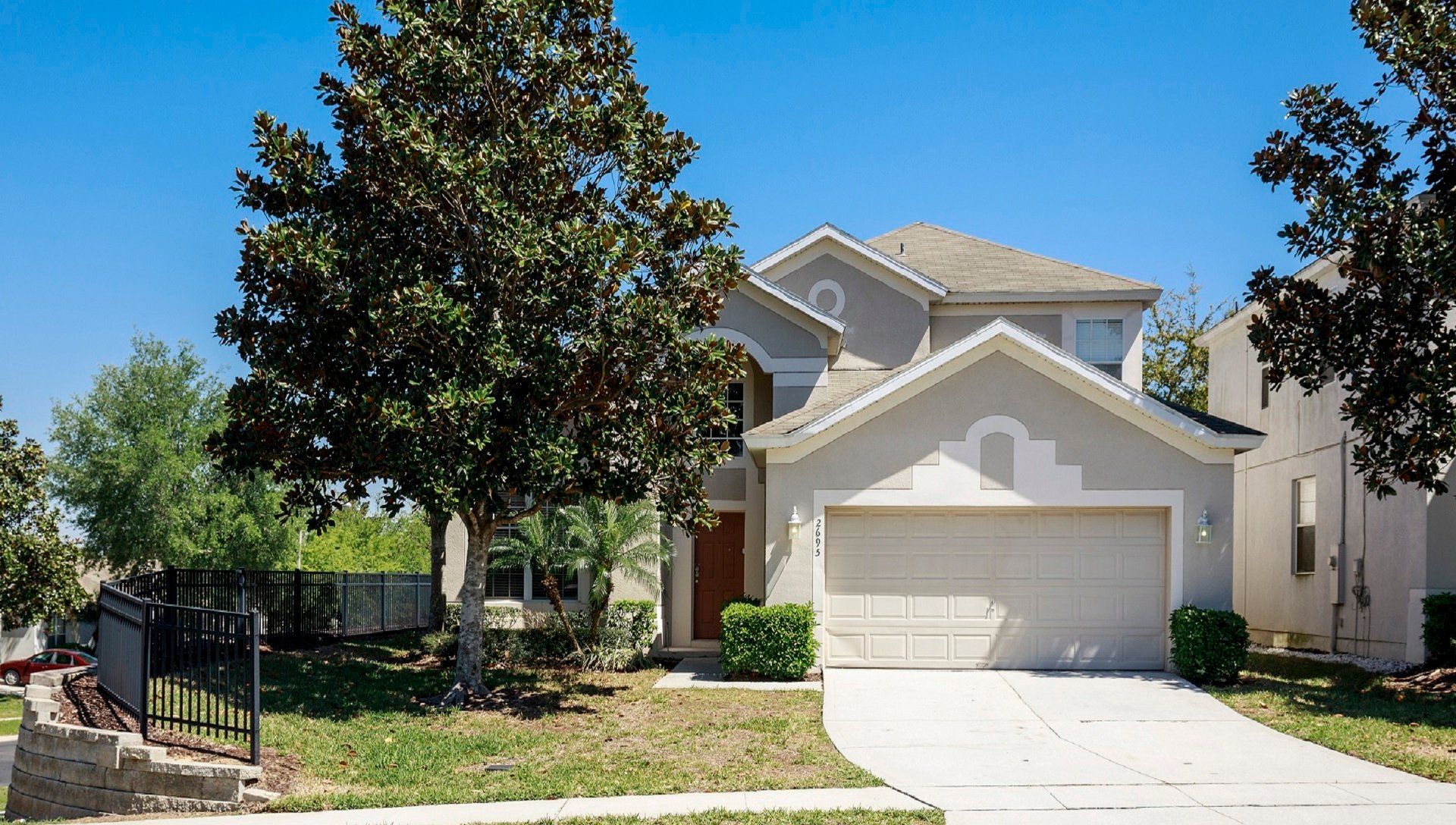 Beautiful modern home with lush greenery, a spacious driveway, and a serene setting.