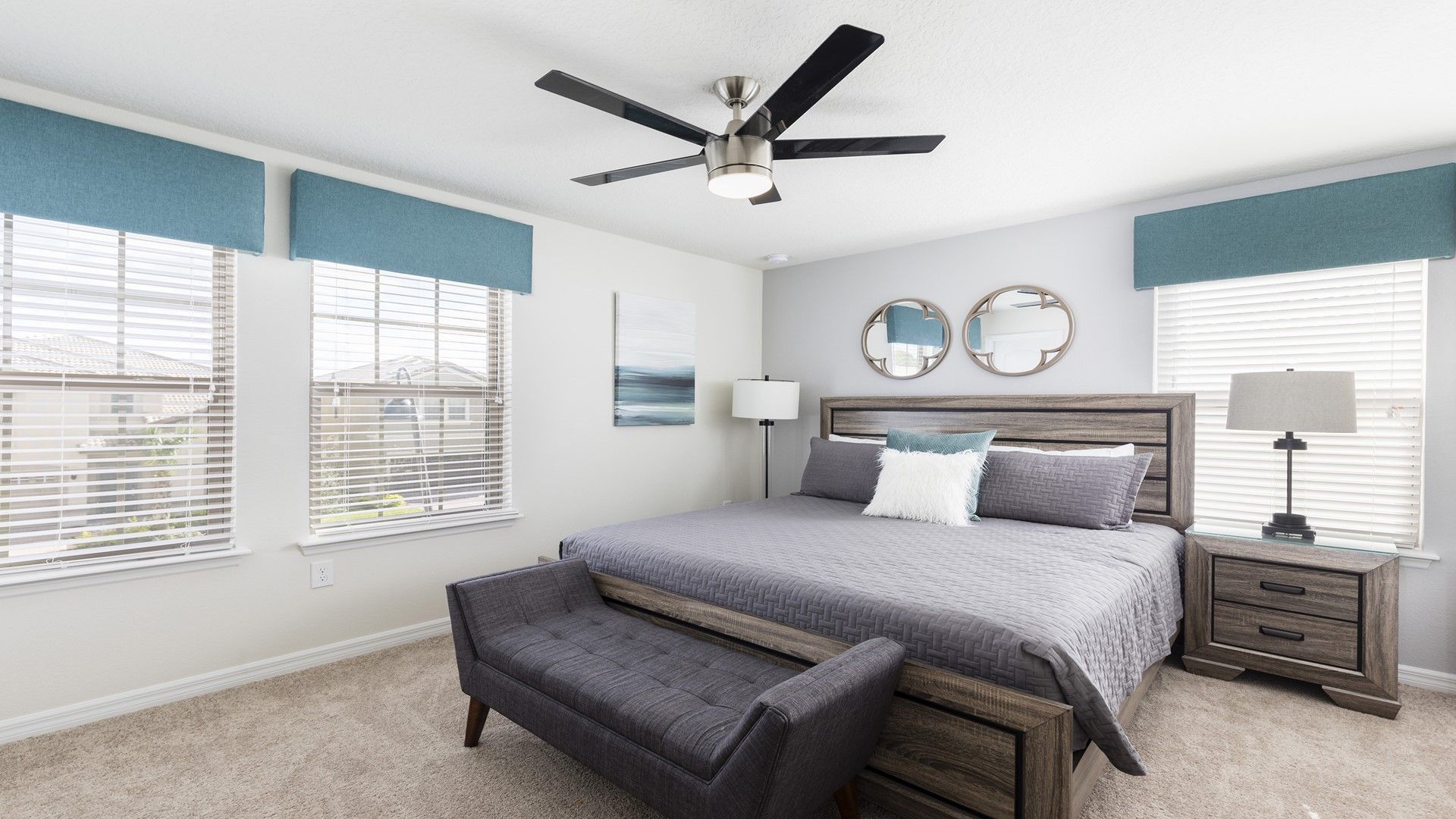 Bright and airy master bedroom with king bed, stylish decor, cozy bench seating, and ceiling fan.