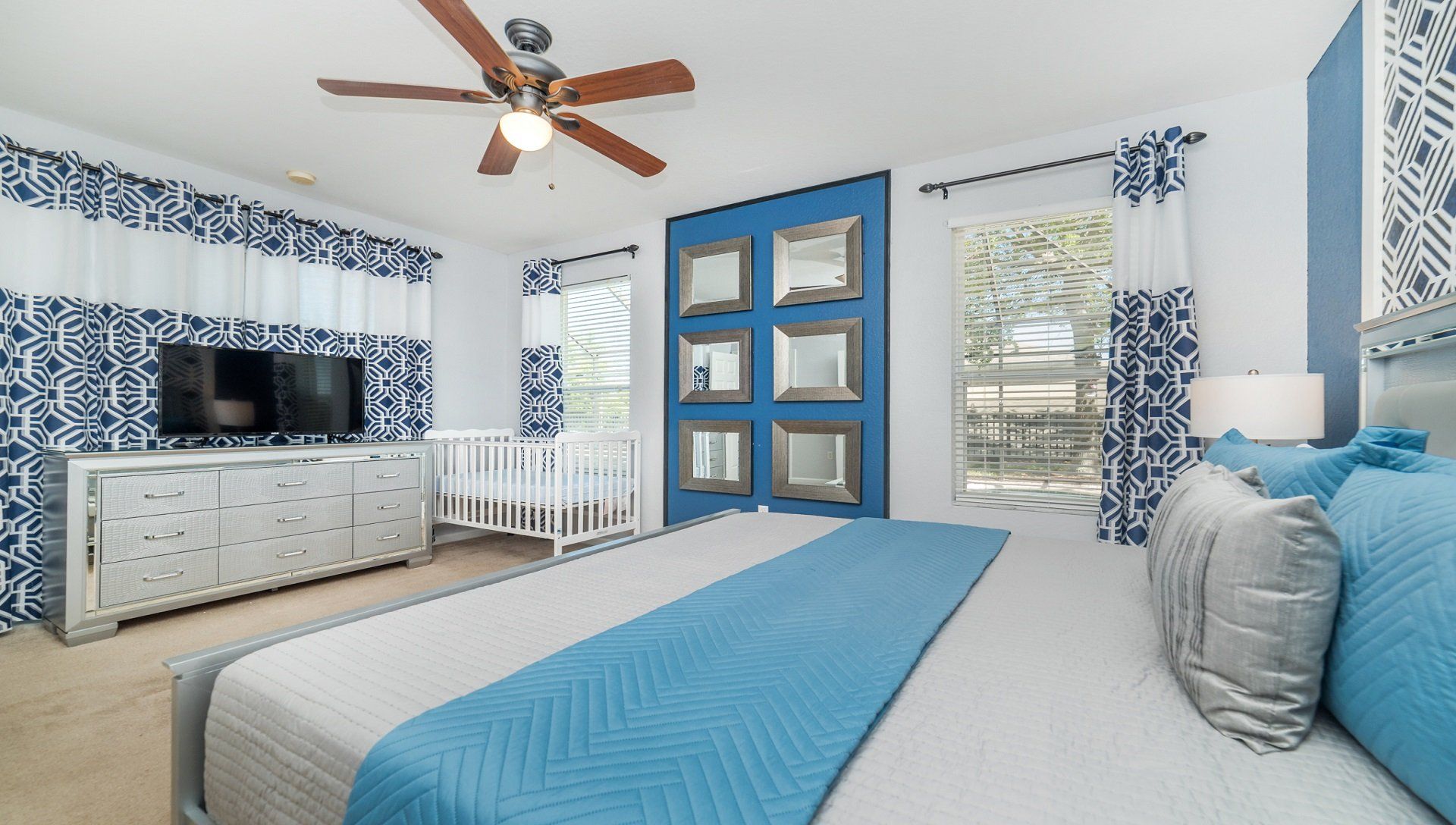 Elegant bedroom with bold blue accents, a cozy crib, and plenty of natural light.