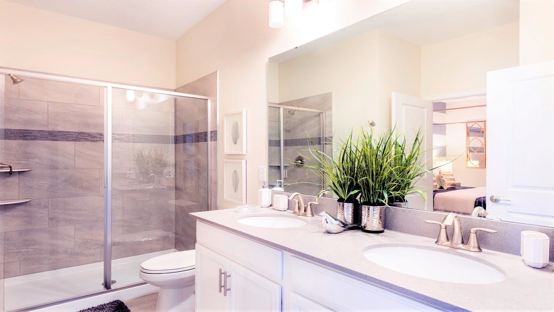 Modern bathroom with double vanity, glass shower, and lush accents