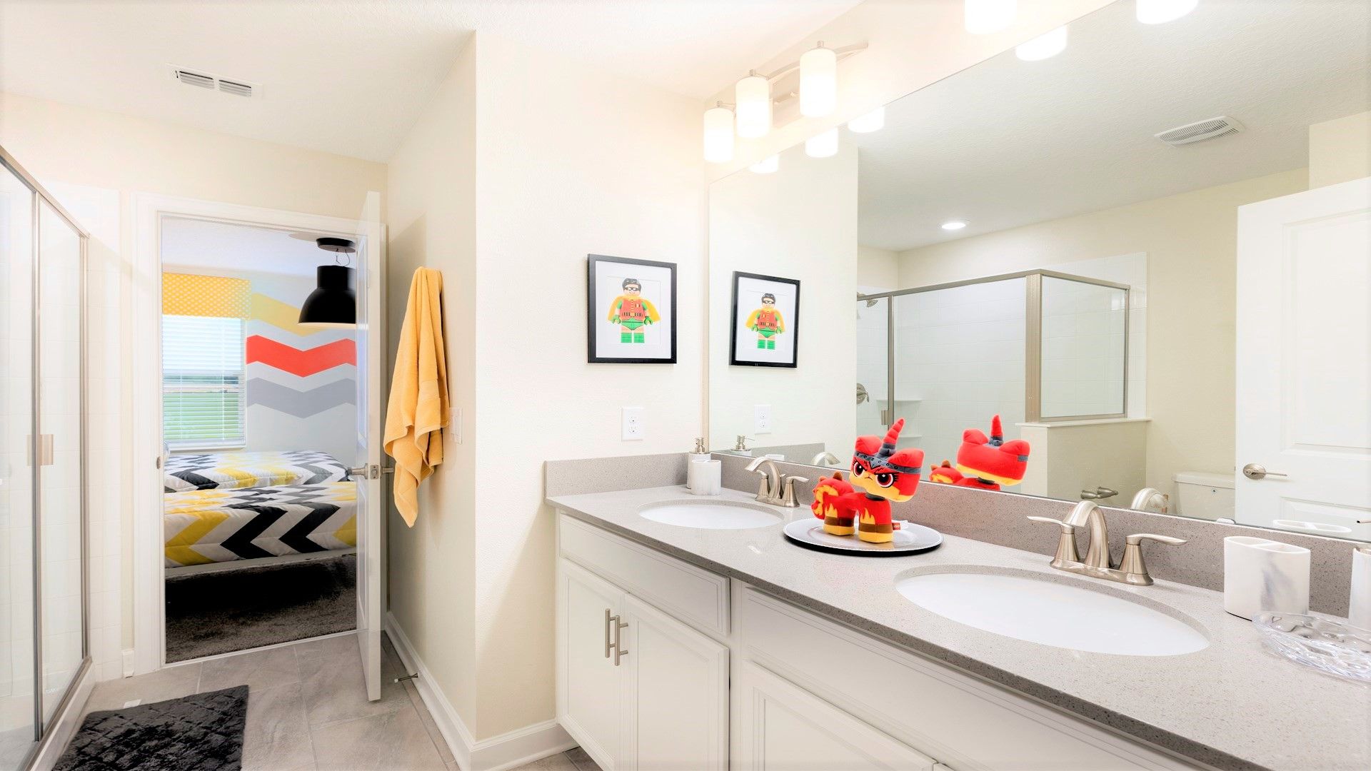 Bright bathroom with double sinks, walk-in shower, and fun decor