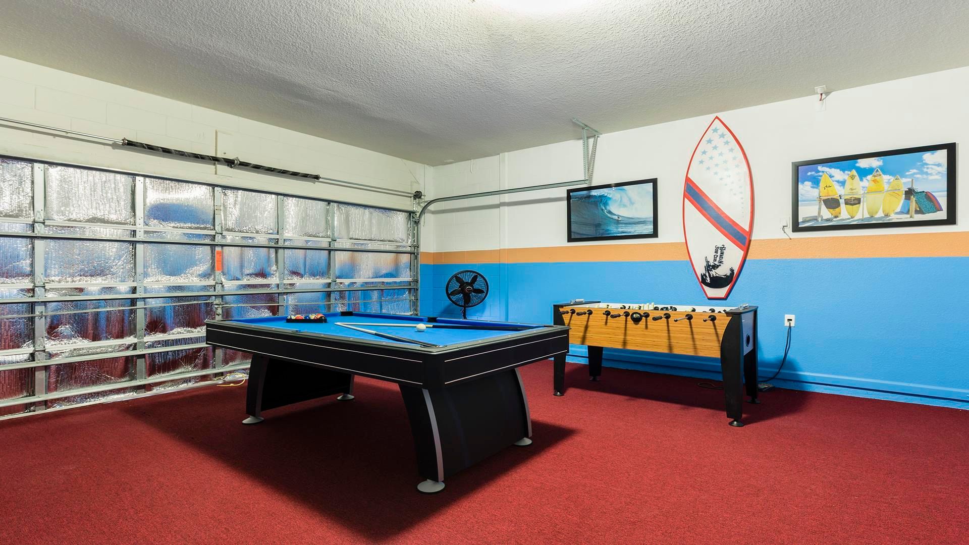 Fun-filled game room with pool table, foosball, and vibrant surfing decor accents.