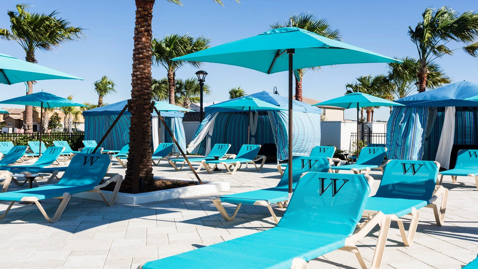Luxurious cabanas and turquoise lounge chairs under palm trees for ultimate relaxation!
