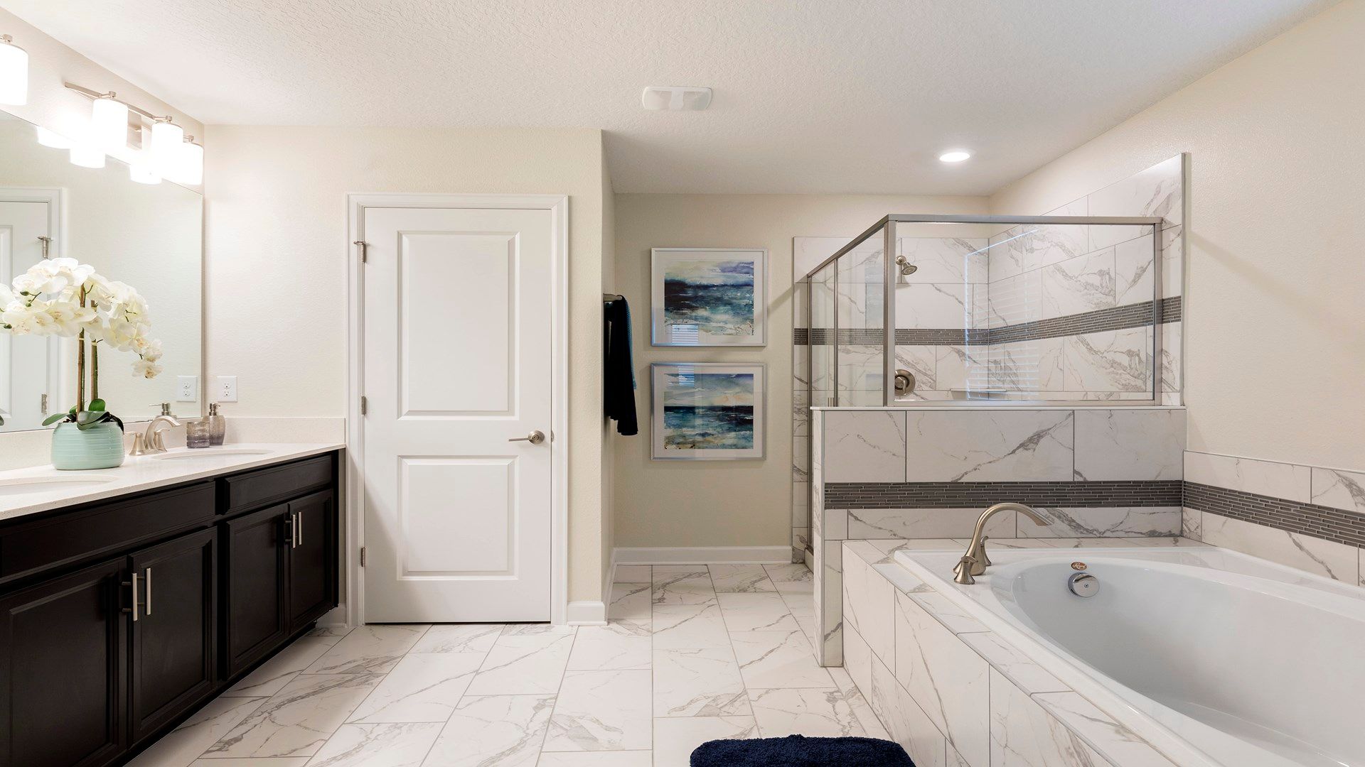 Spacious spa-like bathroom with marble finishes, soaking tub, and glass shower.