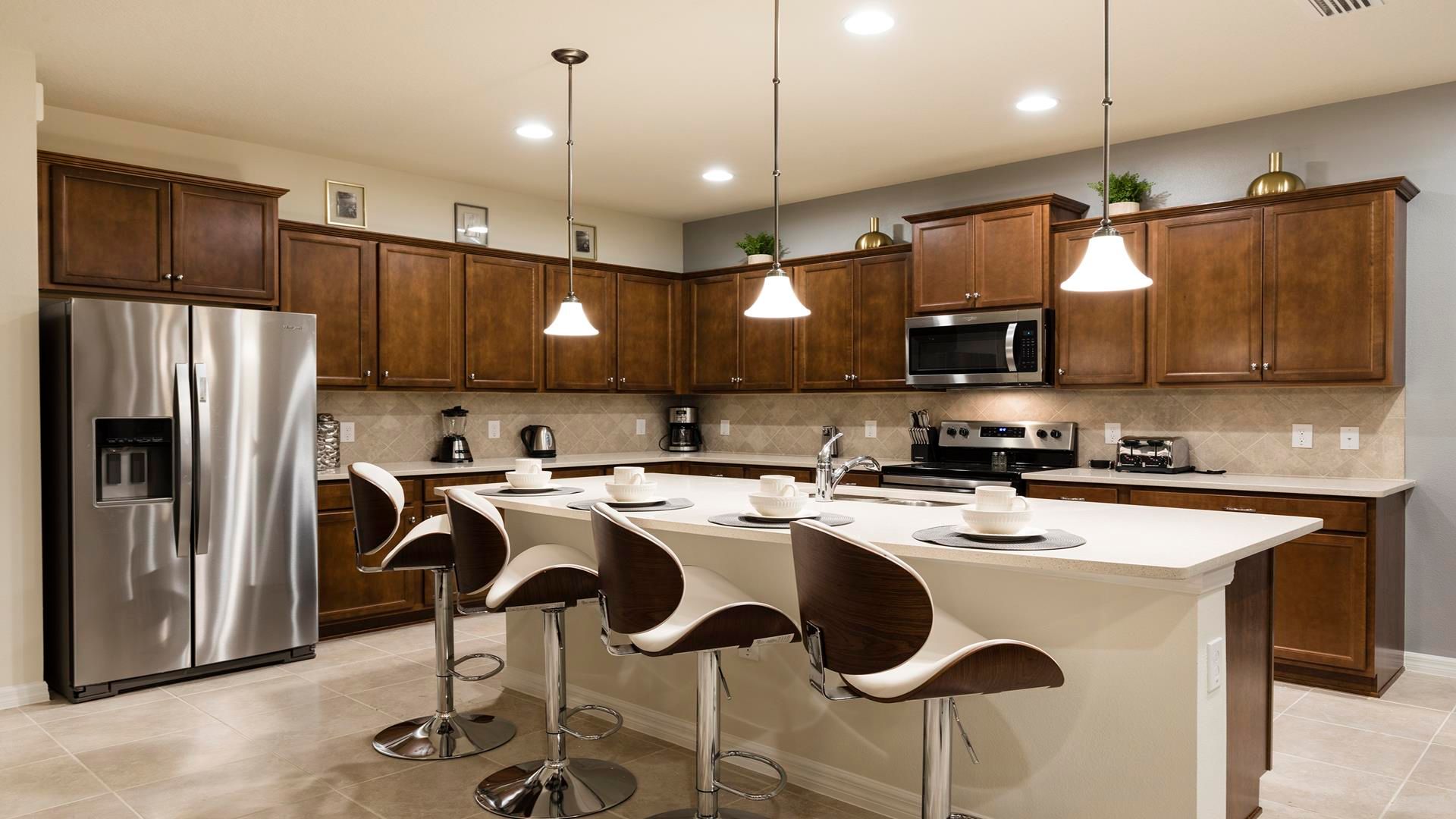 Modern kitchen with stainless steel appliances, island seating & warm lighting!