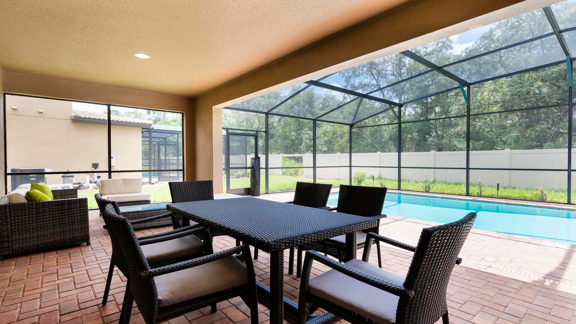 Covered patio with outdoor dining, cozy seating, and poolside views!