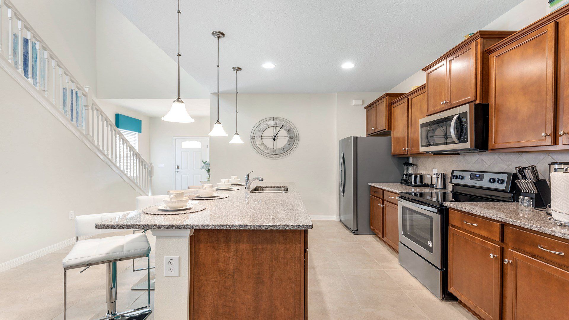 Spacious kitchen with granite counters, modern lighting, and stainless appliances.