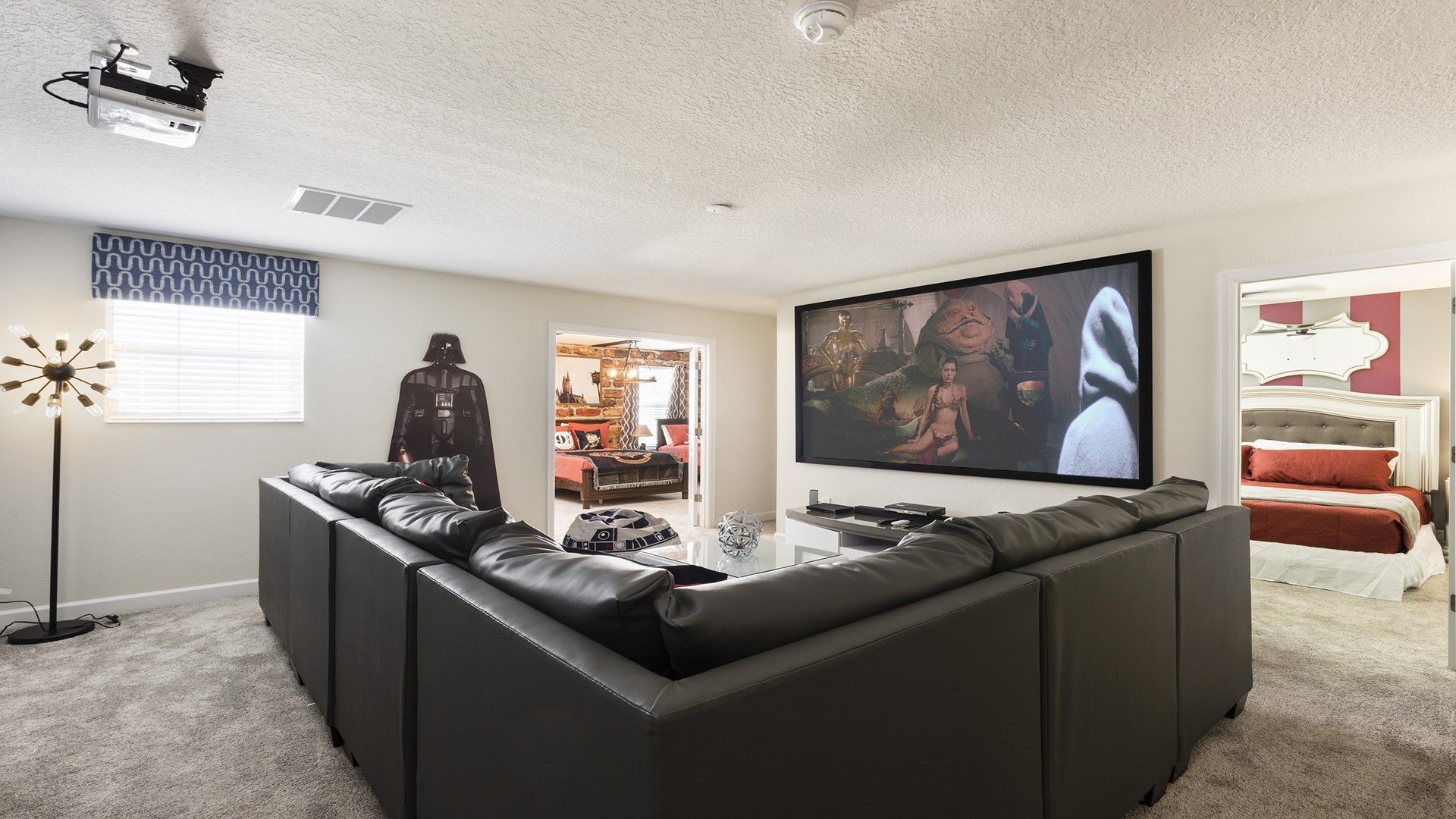 Home theater with a Star Wars theme, featuring a large screen, Darth Vader cutout, and cozy seating.