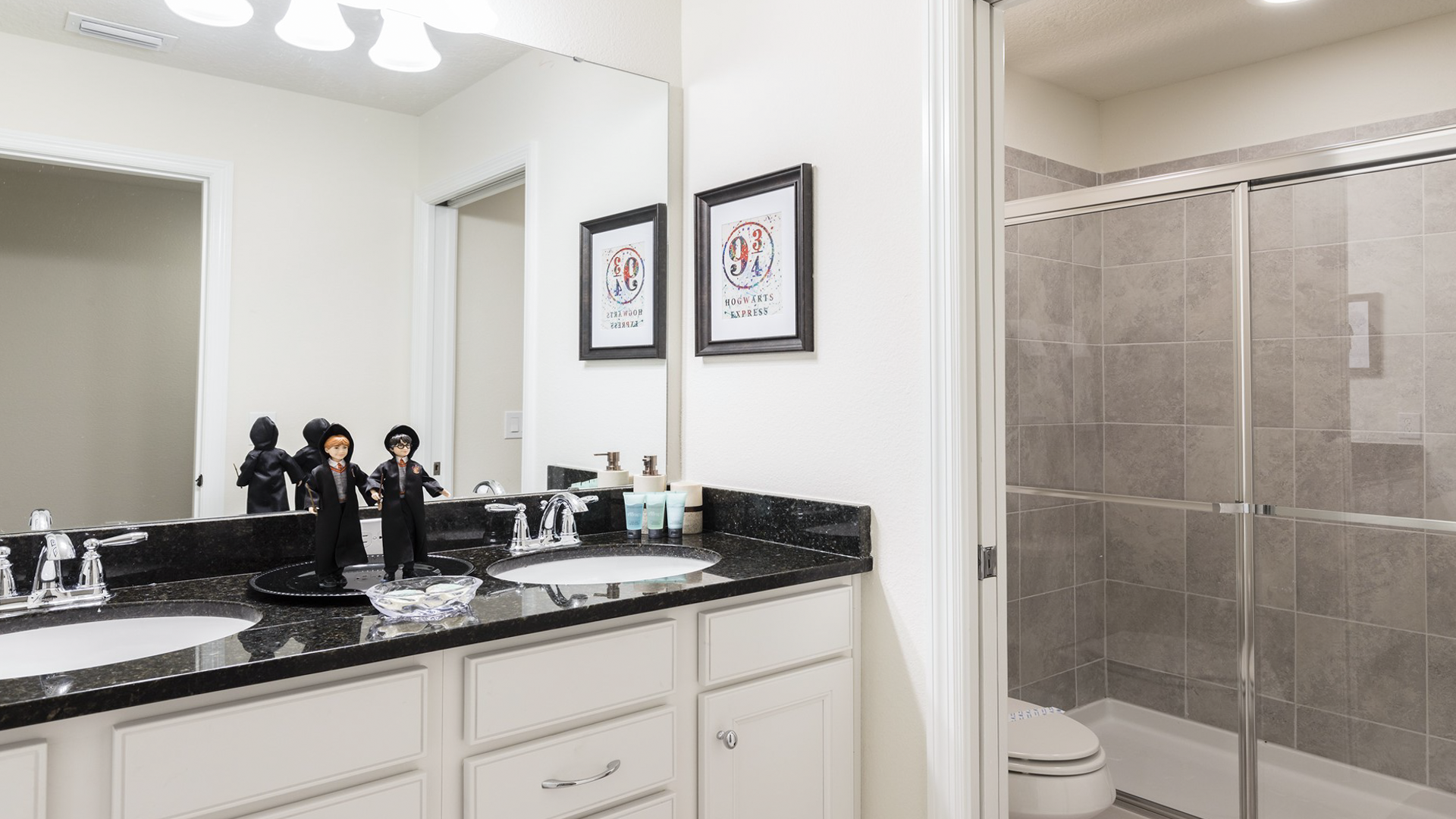 Enchanting themed bathroom with double sinks, granite countertop, and glass shower—magical touches included.
