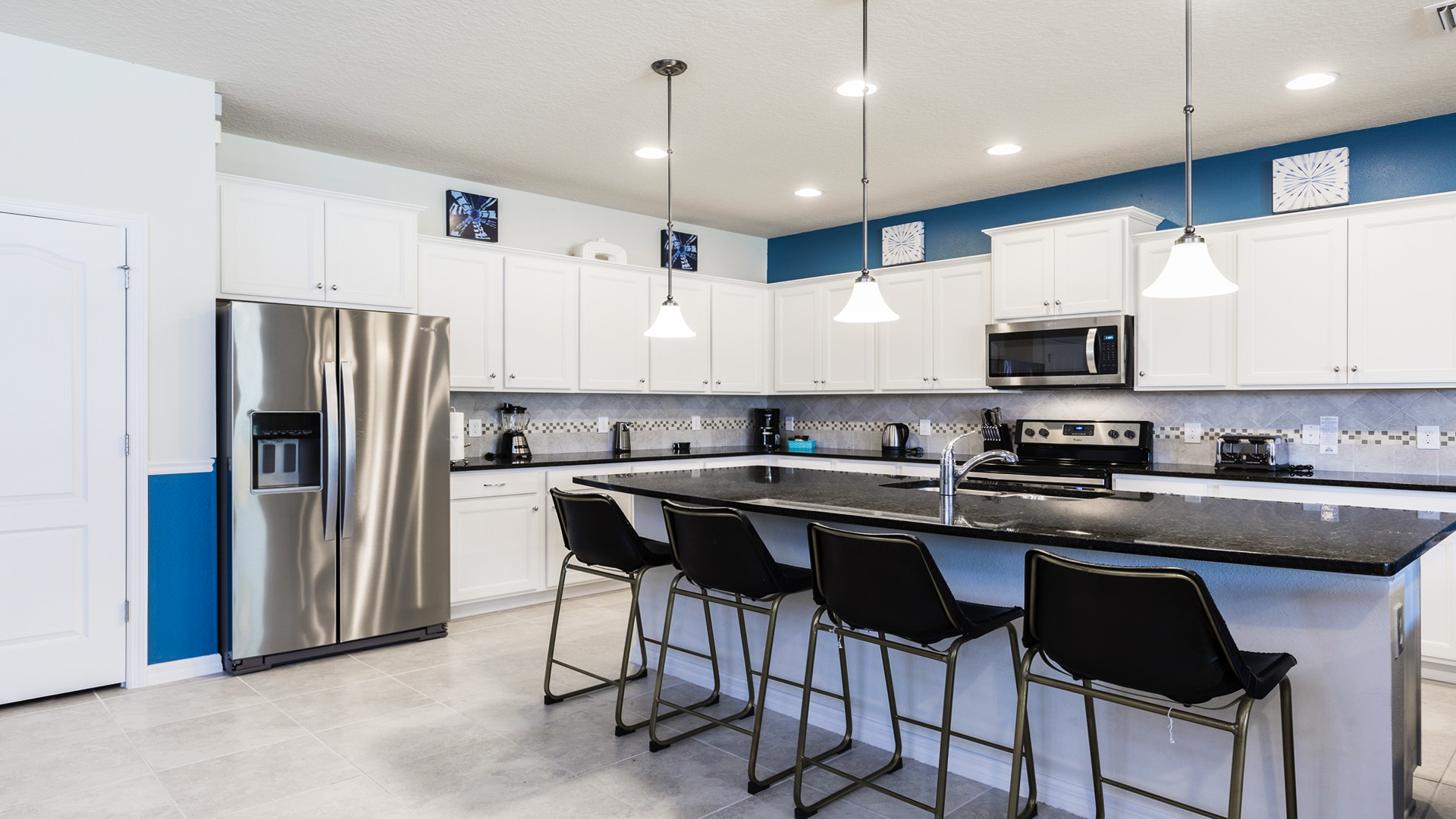 Spacious, fully equipped kitchen with stainless steel appliances, granite countertops, and bar seating.