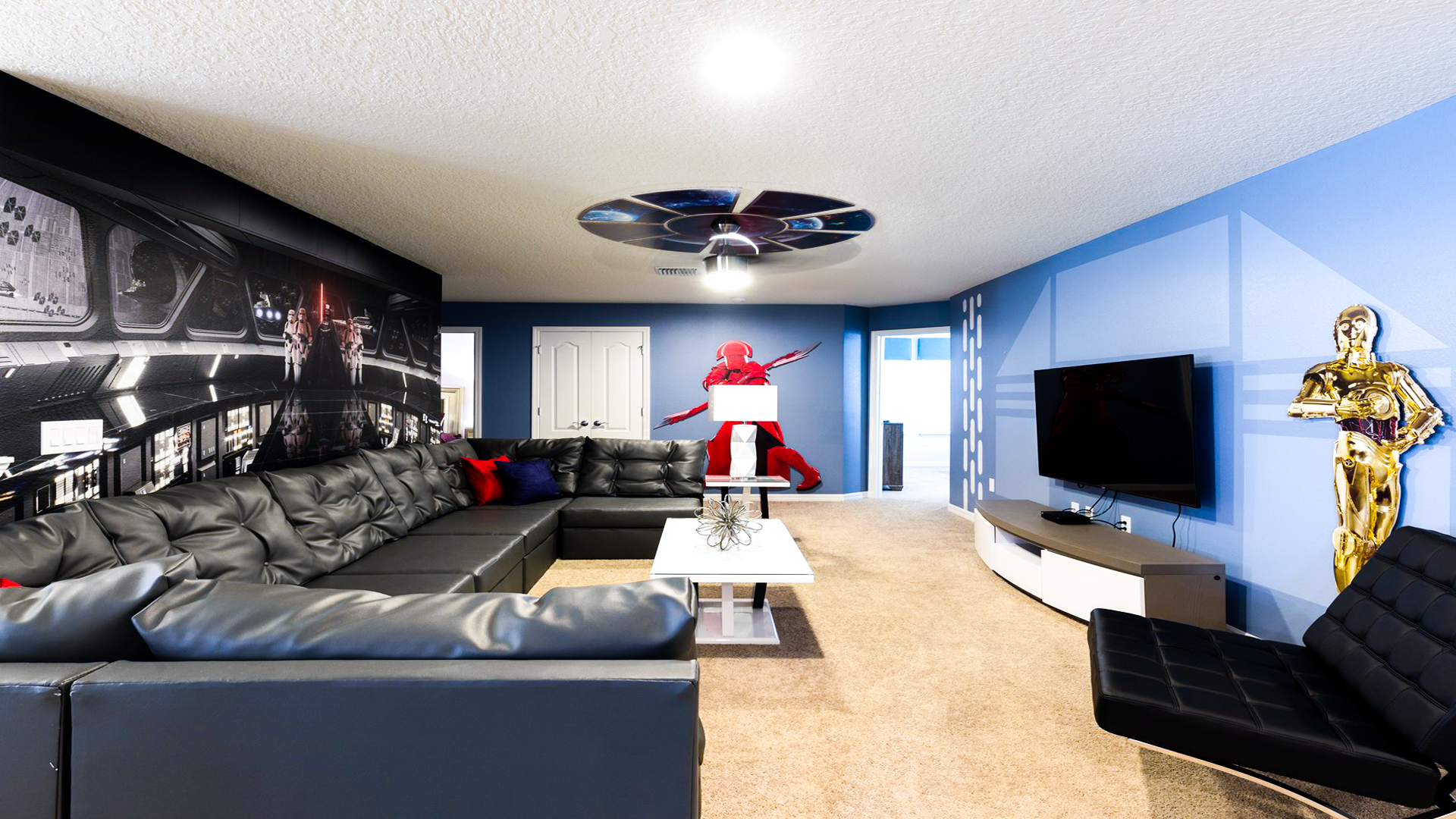 Epic Star Wars-themed lounge with movie mural, plush sectional, and life-size character statues.