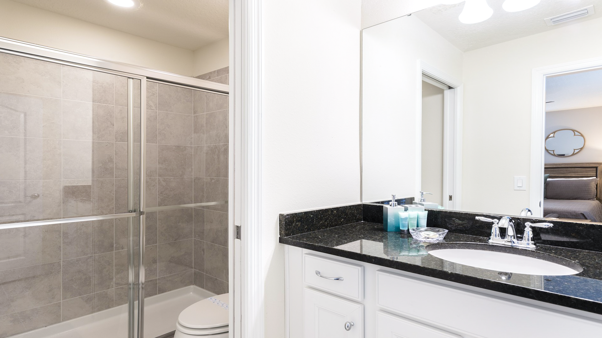 Modern bathroom with sleek granite countertop, glass shower, and convenient bedroom access.
