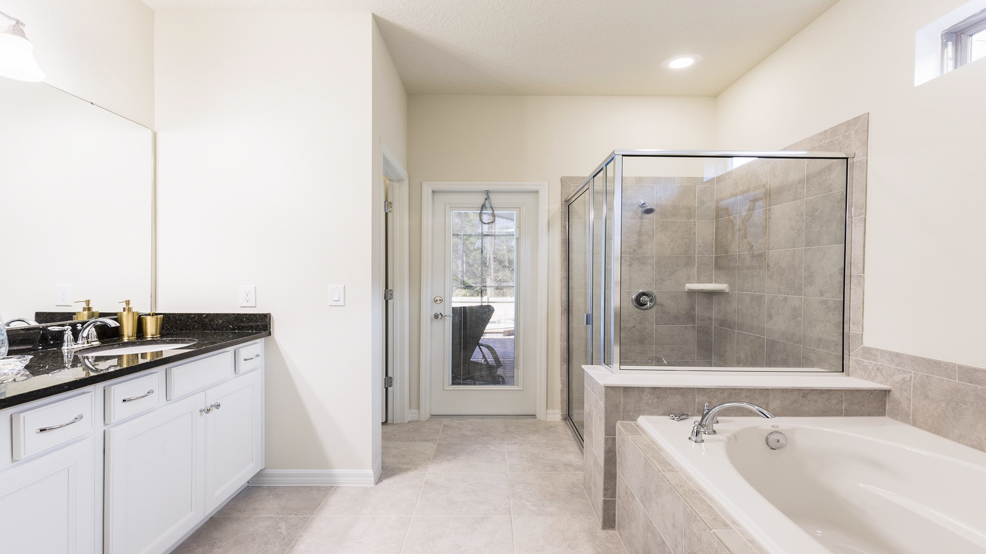 Luxurious master bathroom with dual sinks, soaking tub, glass shower, and direct patio access.