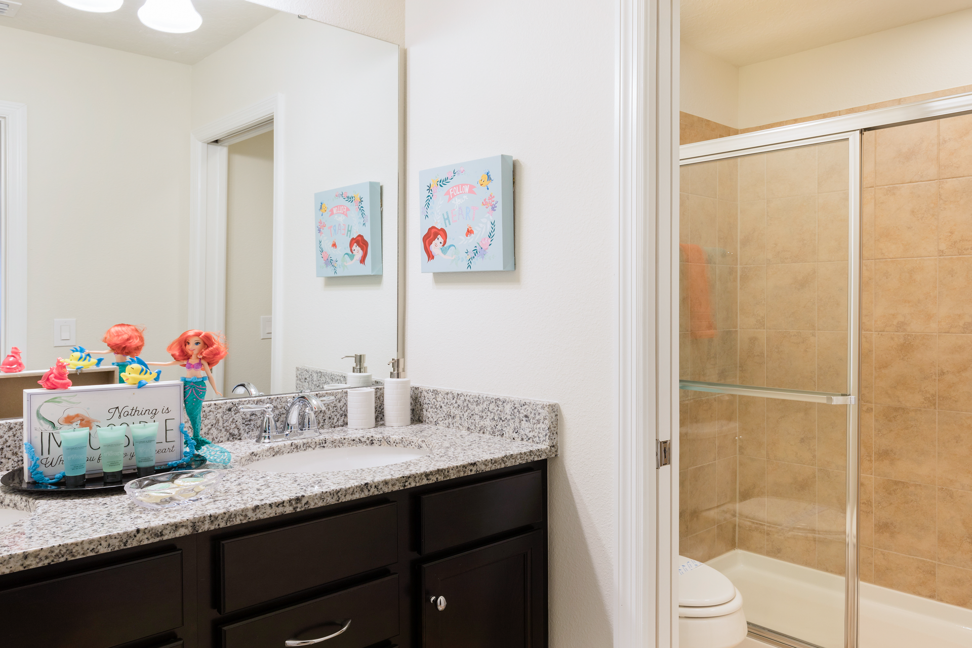 Charming kids’ bathroom with granite counters, fun decor, and a walk-in shower.