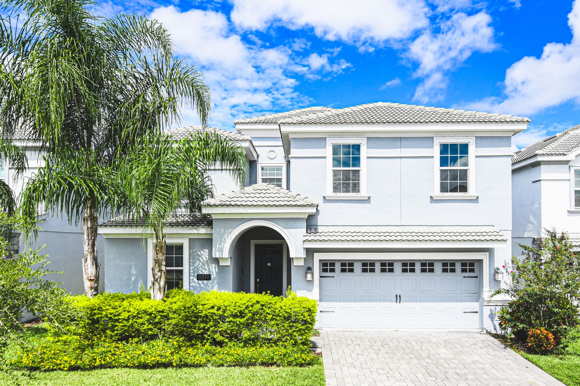 Elegant white home with lush greenery and a convenient garage