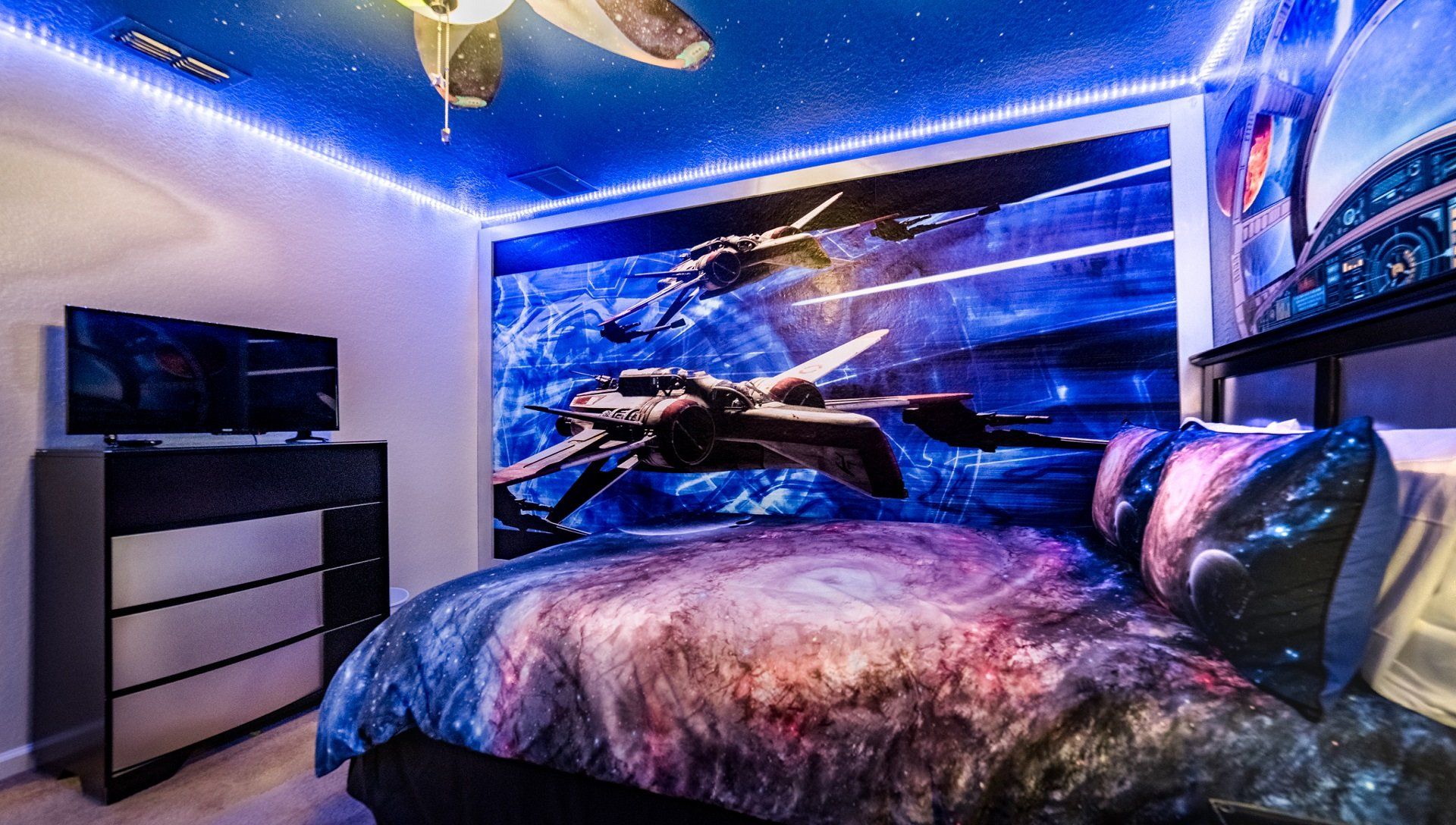 Epic space-themed bedroom with glowing LED lights, galaxy bedding, and starship decor.