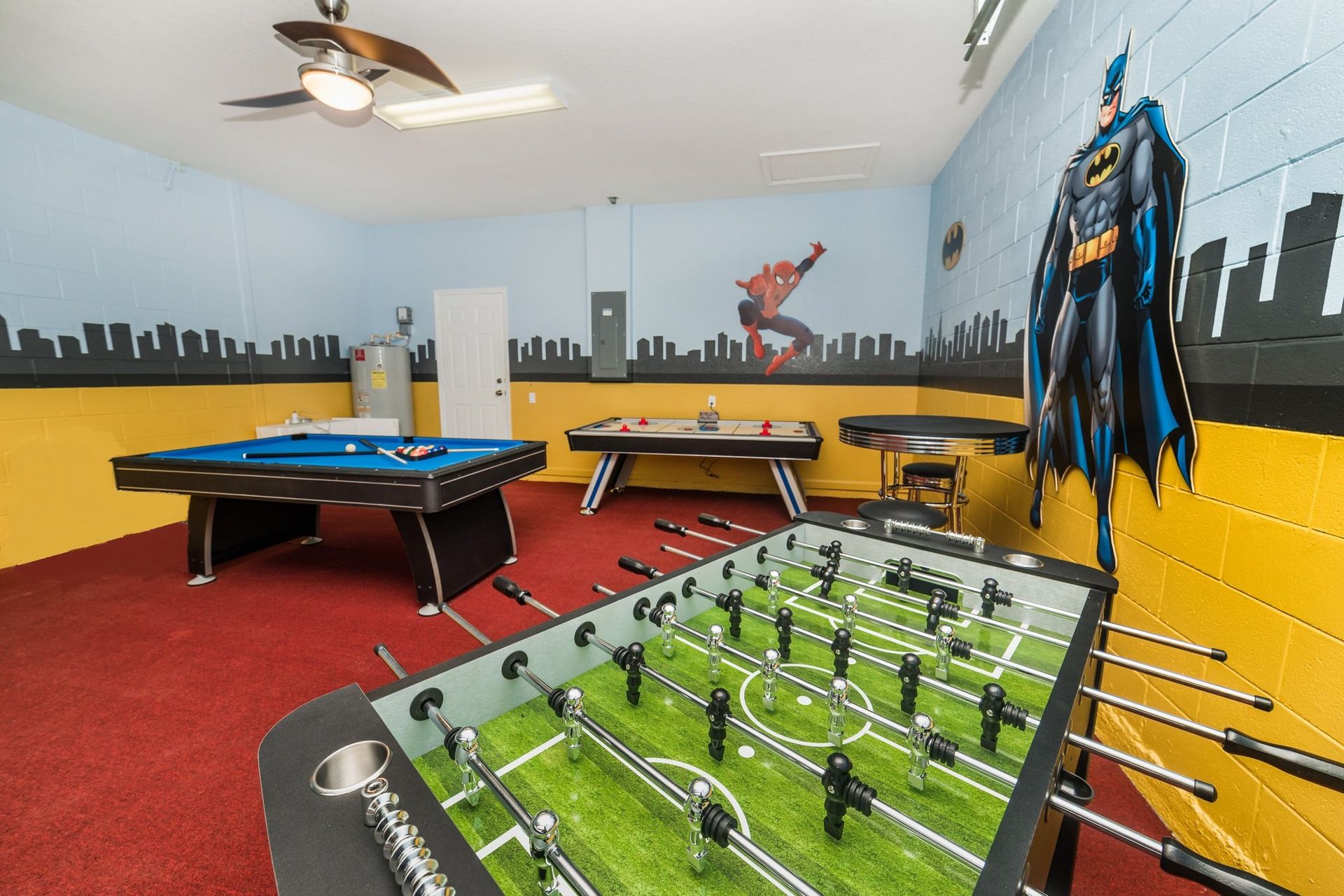 Superhero-themed game room with pool, foosball, air hockey, and vibrant decor.