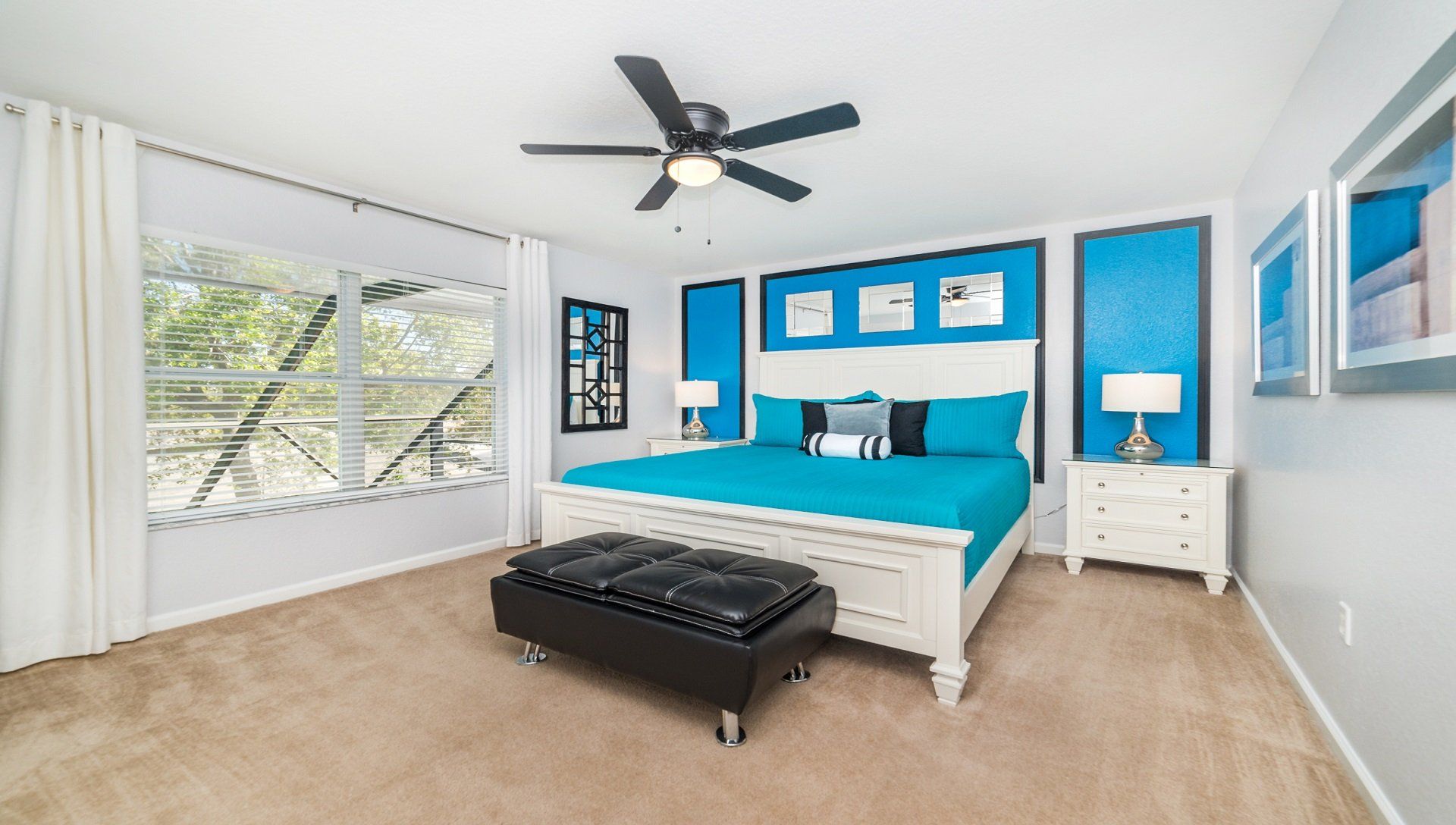 Spacious, stylish bedroom with bold blue accents, natural light, and cozy seating.