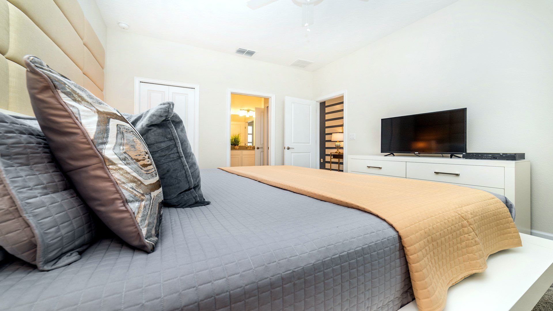 Modern bedroom with soft bedding, a sleek TV, and en-suite bathroom