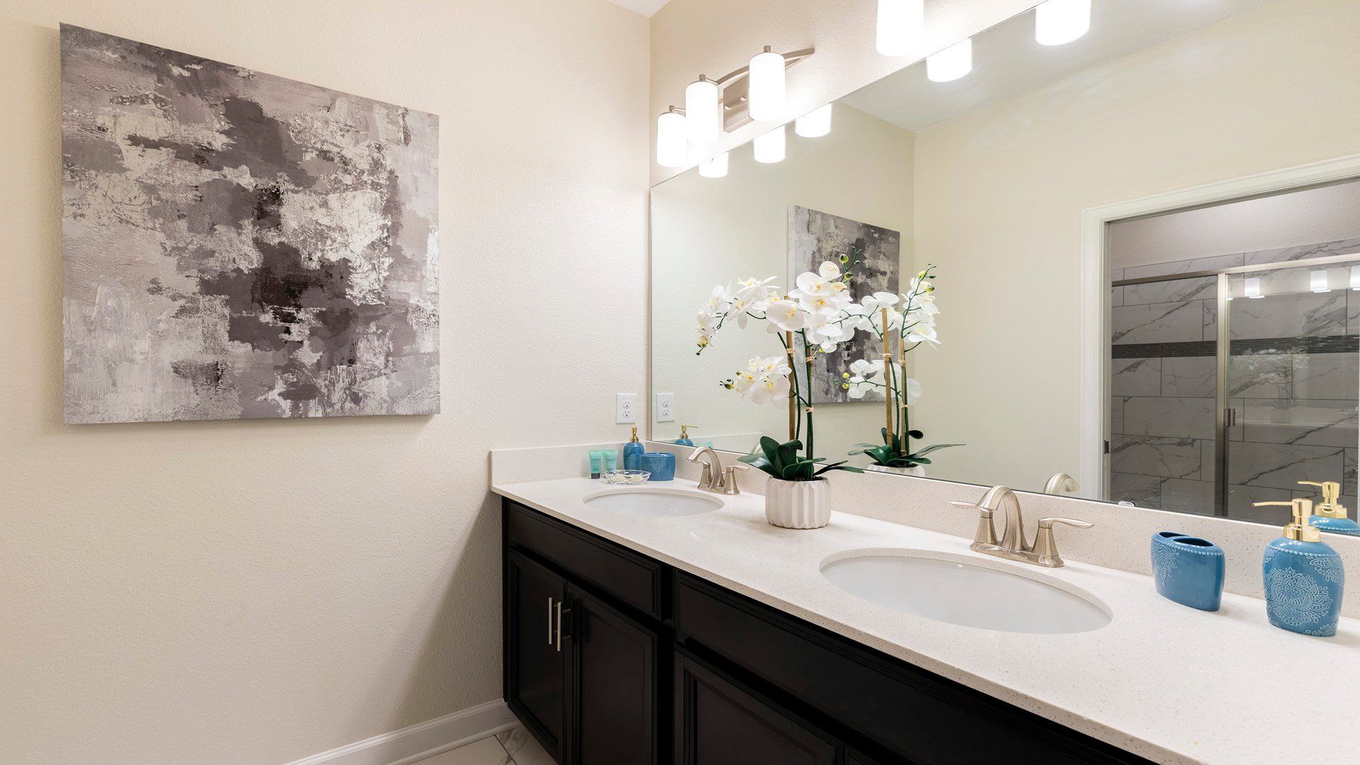 Elegant bathroom with dual sinks, glass shower, and chic floral accents.