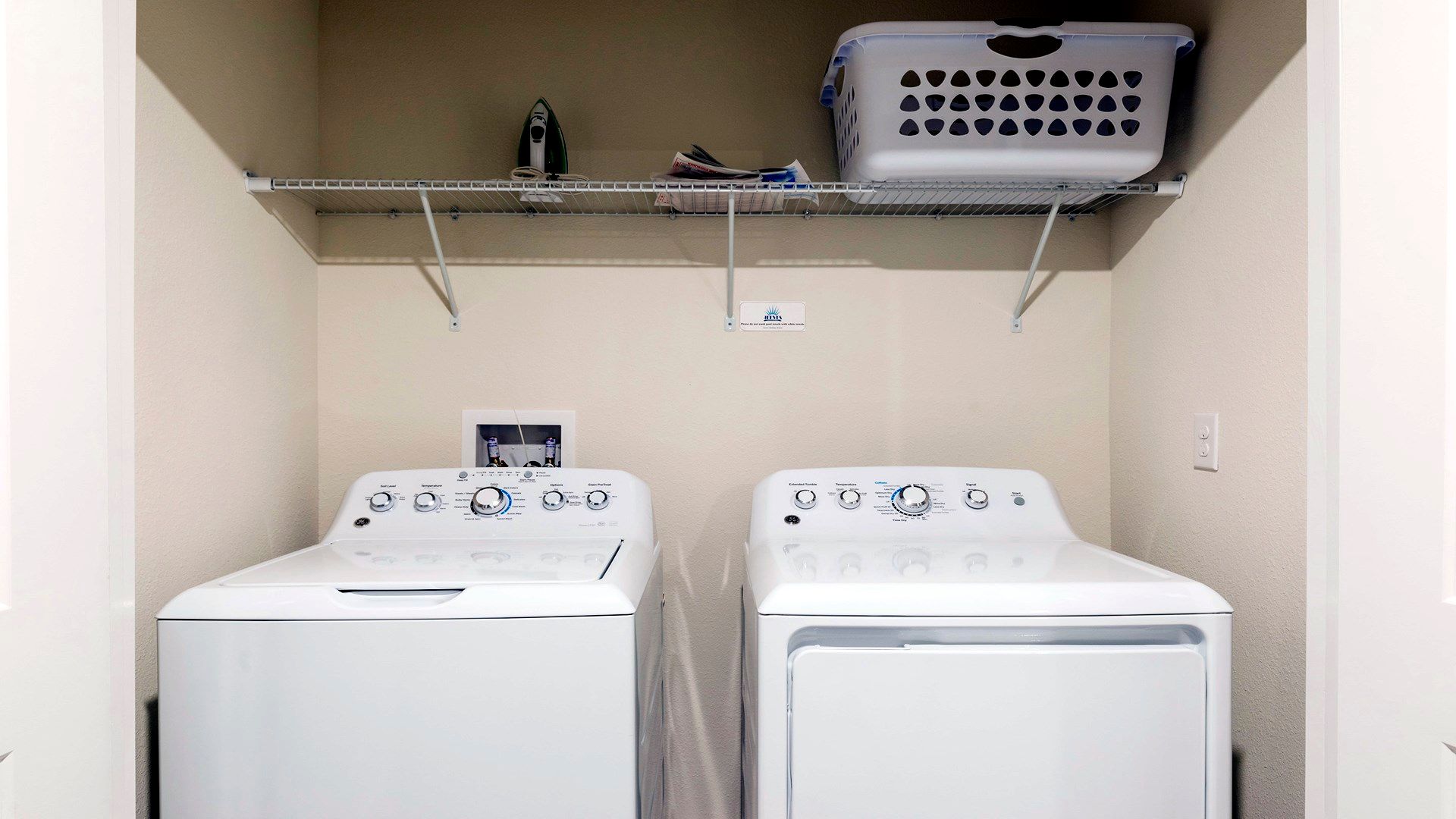 Convenient laundry room with washer, dryer, and ample shelving.