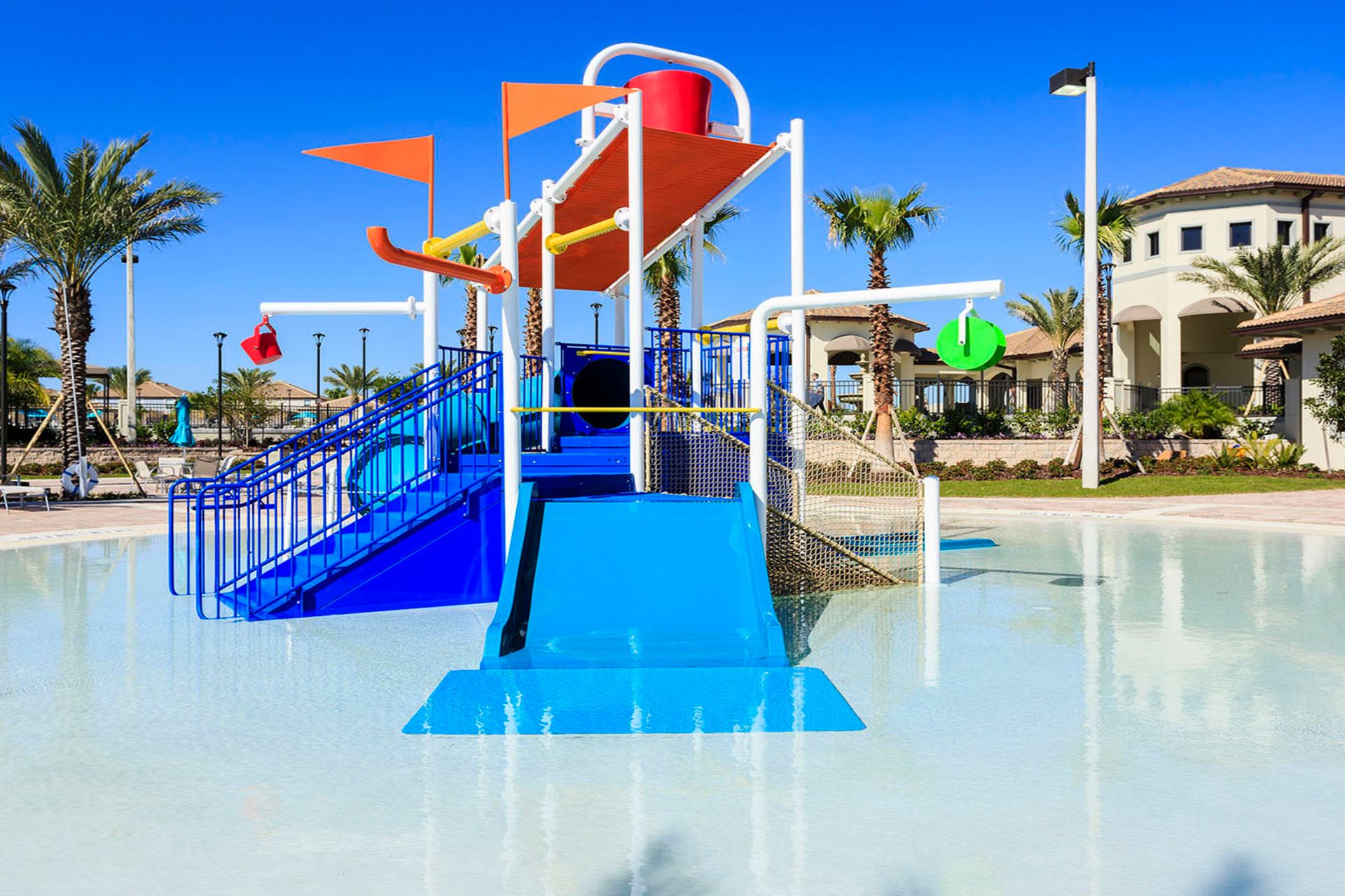 Resort-style splash pad with water slide and tropical ambiance.